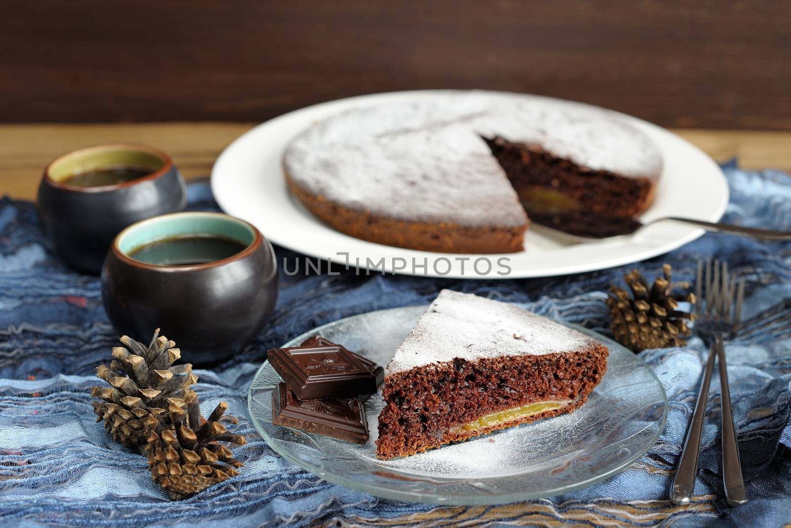 Chocolate cake with pine cones and black tea on blue cloth by Borodin