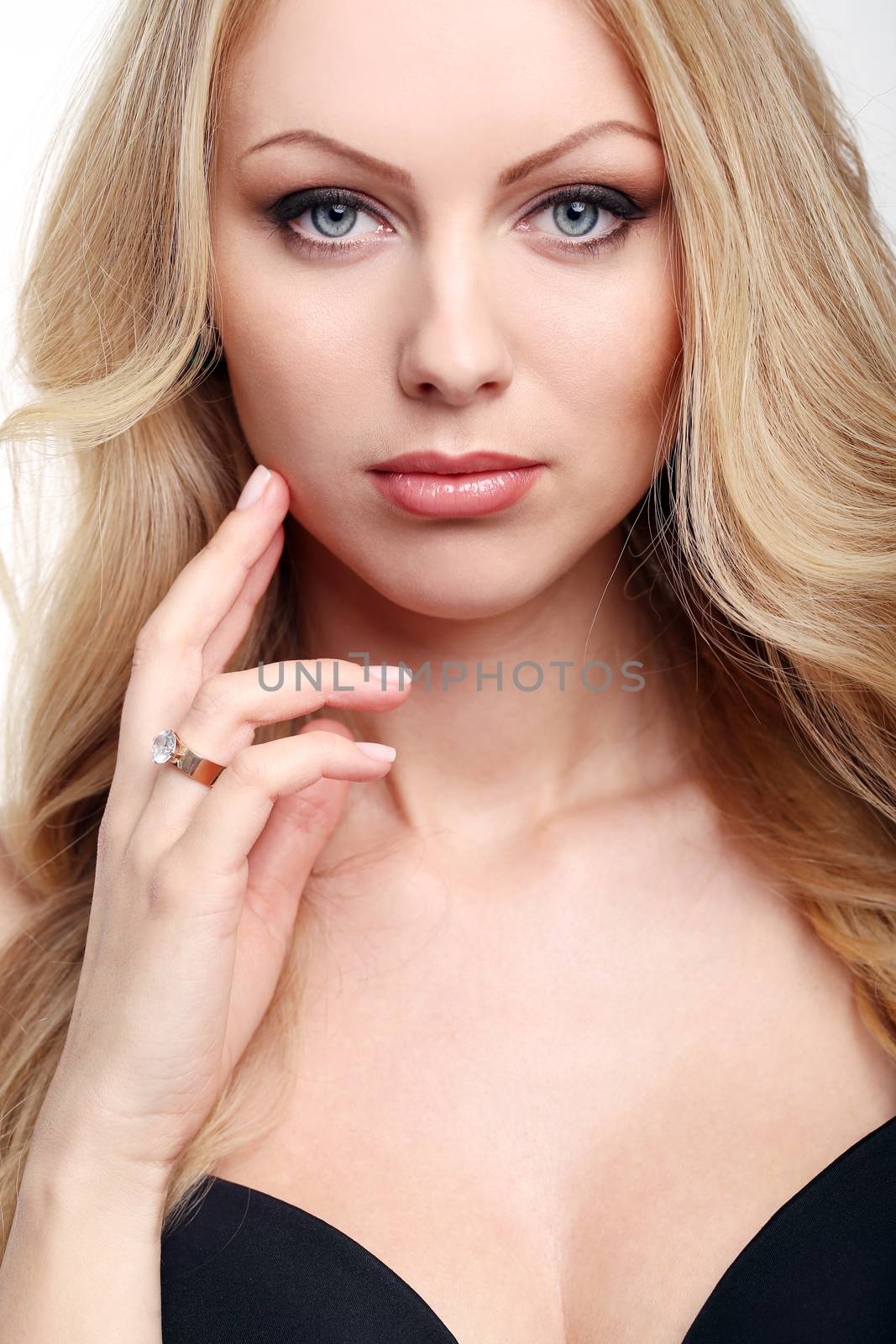 Portrait of a beautiful girl with blonde and curly hair who is posing over a white background