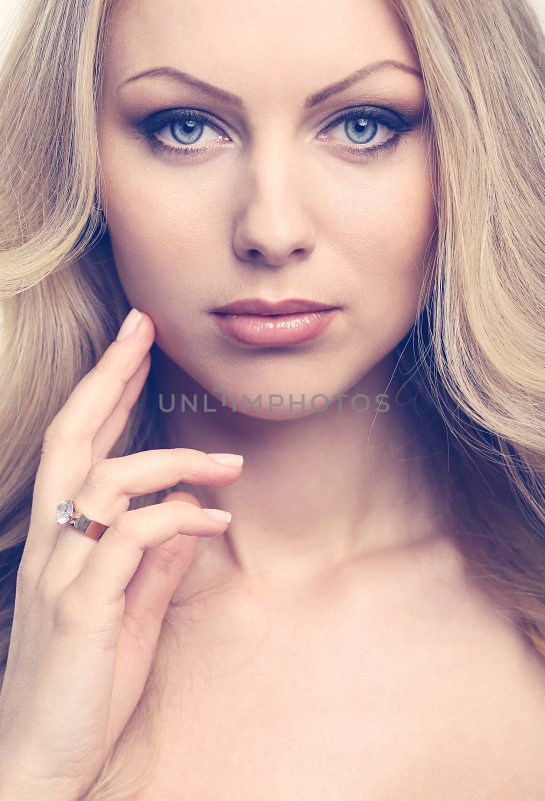 Portrait of a beautiful girl with blonde hair and naked shoulders who is posing over a white background