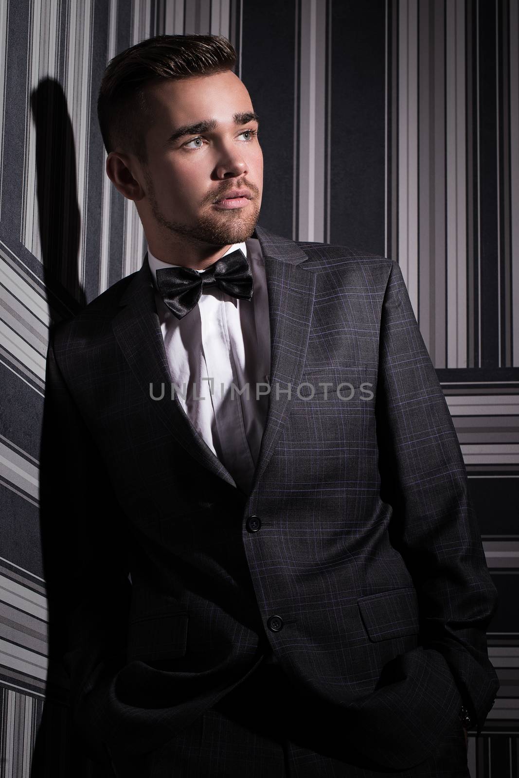 Portrait of a handsome man in a suit and a tie who is posing over a striped background