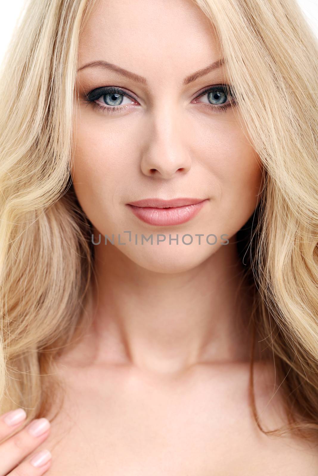 Portrait of a beautiful girl with blonde hair and naked shoulders who is posing over a white background