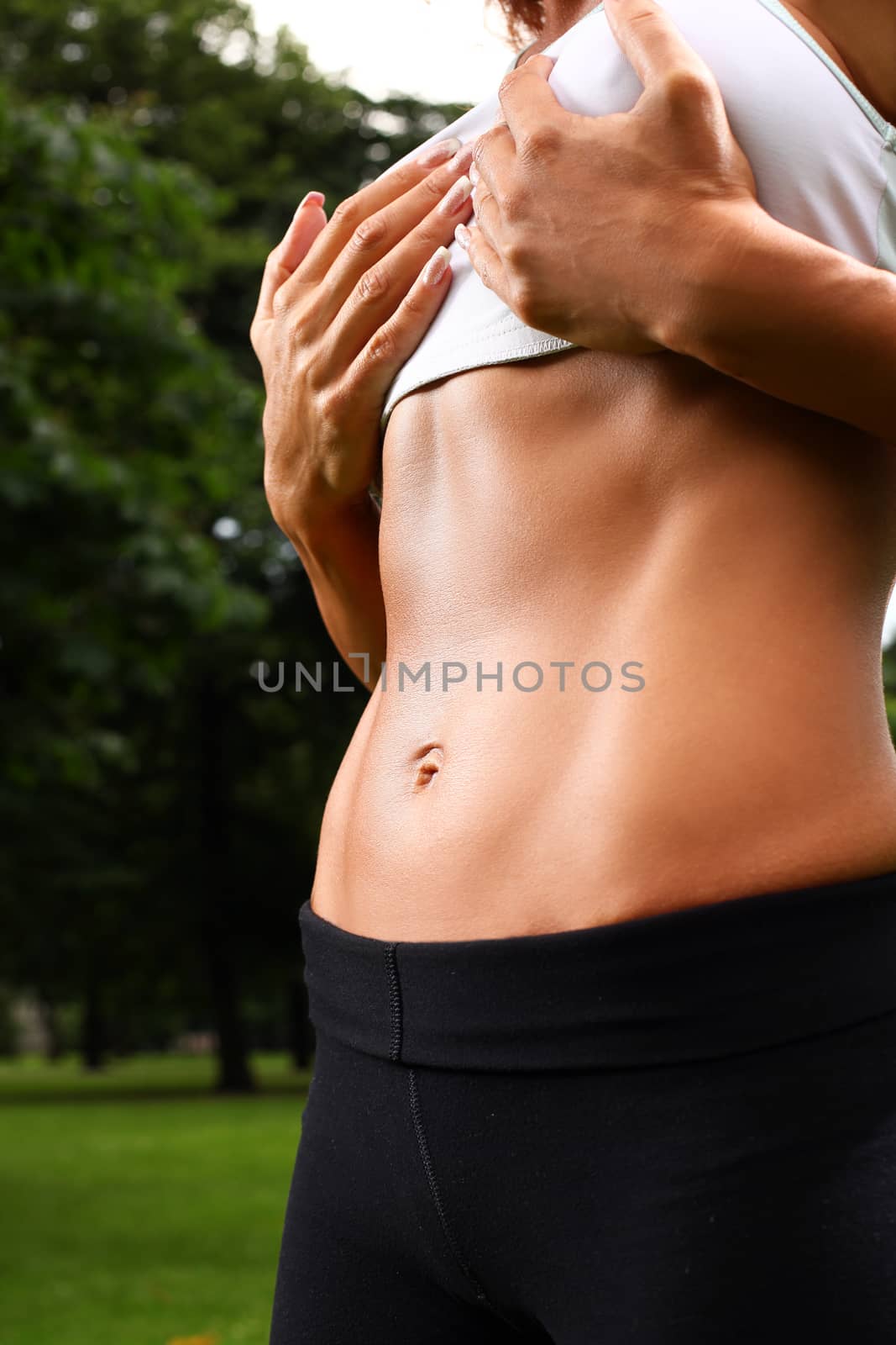 Beautiful caucasian woman's muscular torso in a park