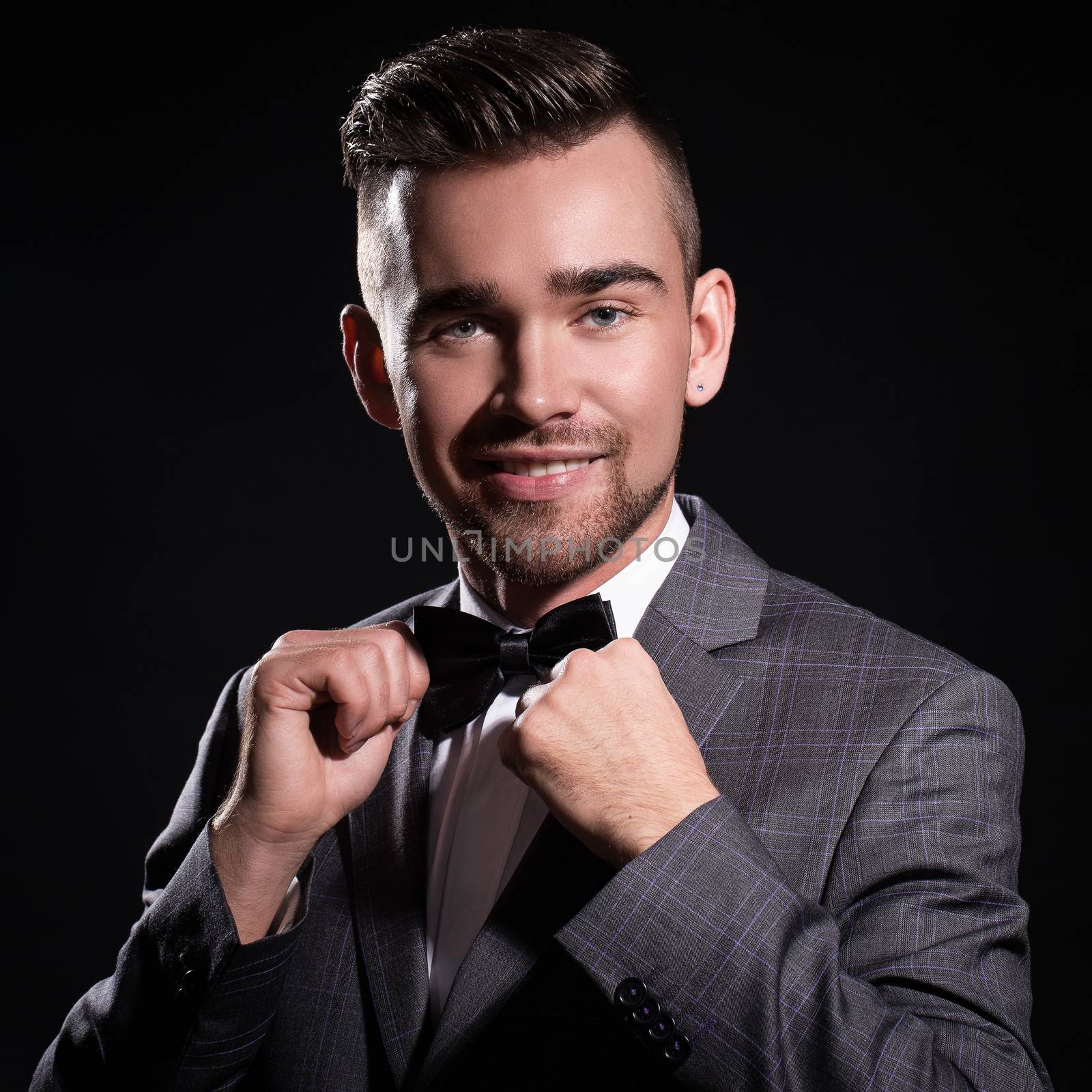 Portrait of a handsome man in a suit who is posing over a black background