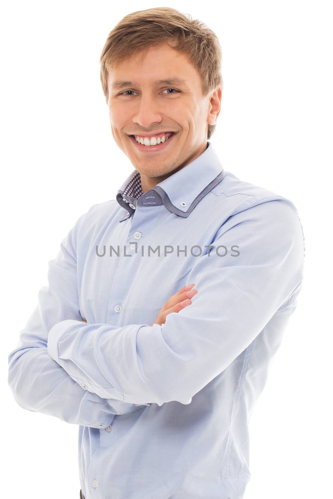 Handsome man in a blue shirt smiles and holds his hands crossed over a white background