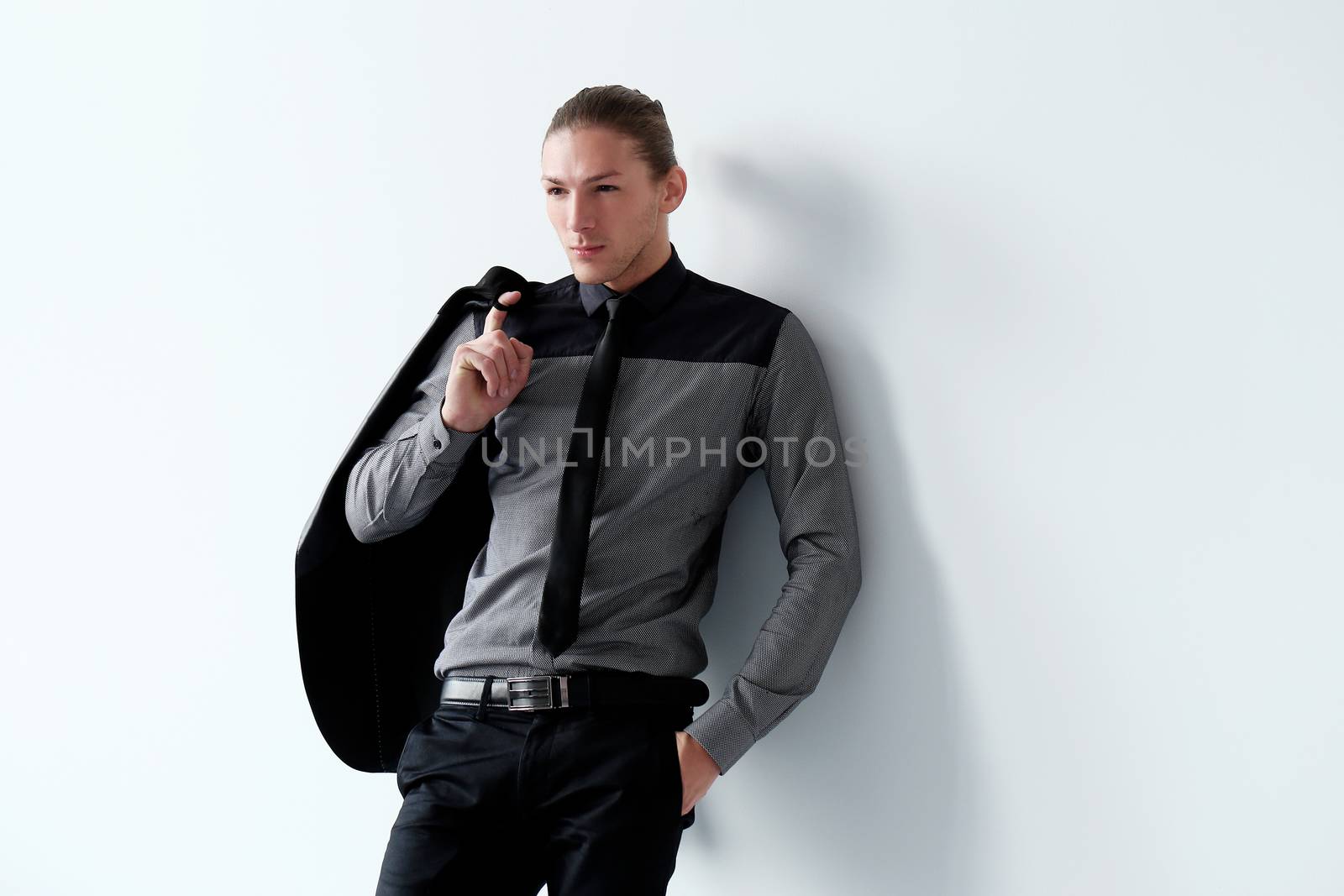 Portrait of a handsome man in a black suit who is posing over a white background