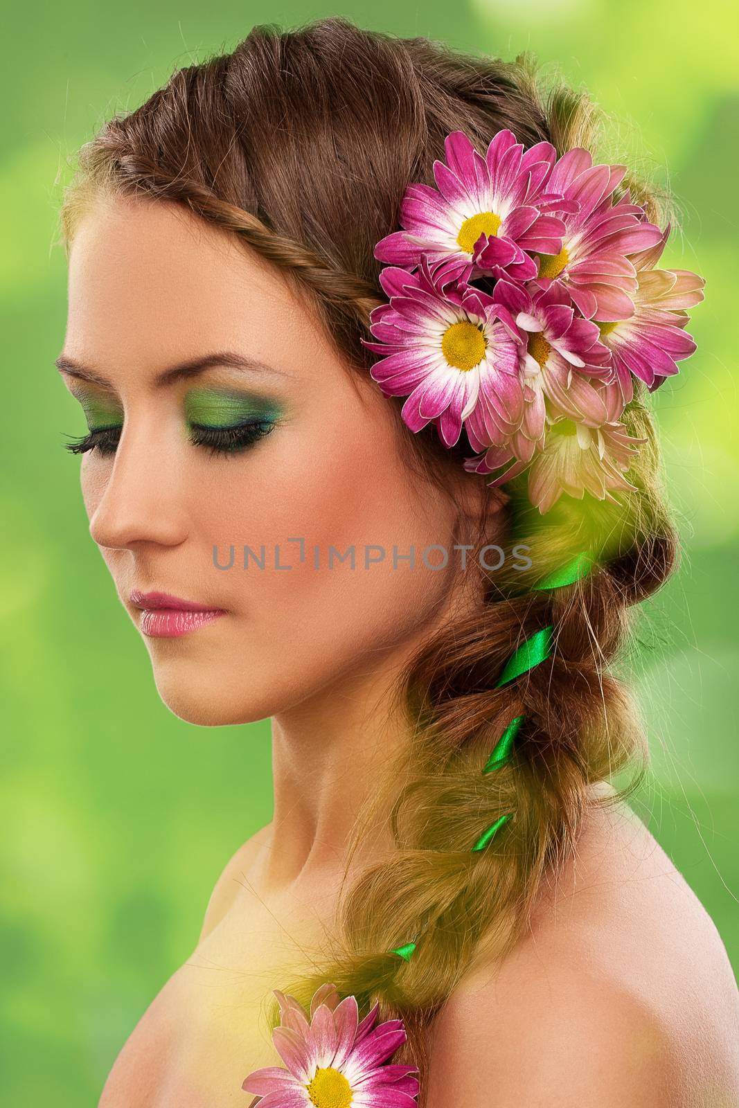 Beautiful woman with makeup and flowers over green background