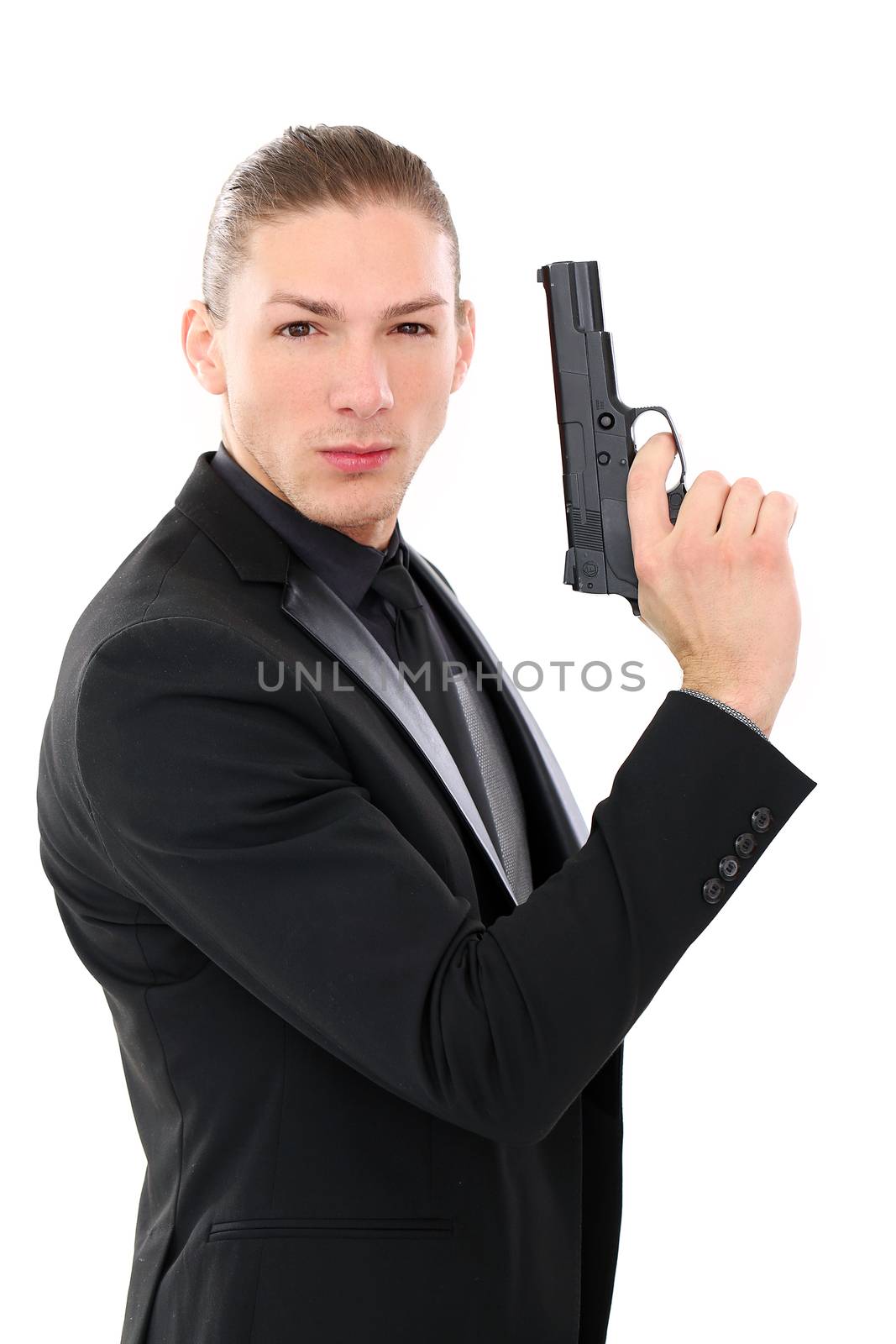Handsome man in a black suit and a pistol posing over a white background