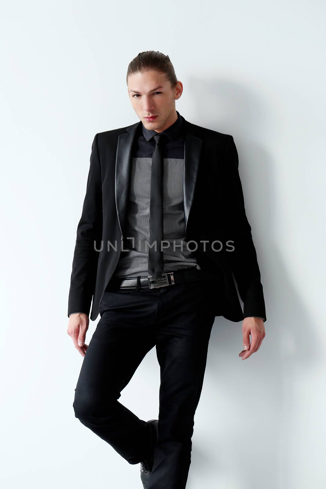 Portrait of a handsome man in a black suit who is posing over a white background