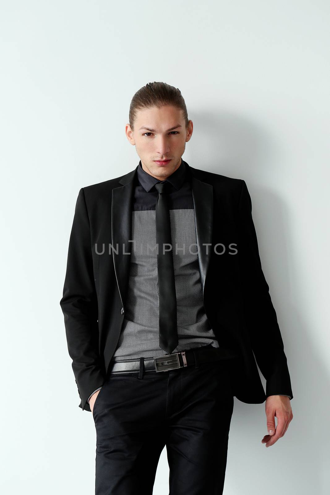 Portrait of a handsome man in a black suit who is posing over a white background