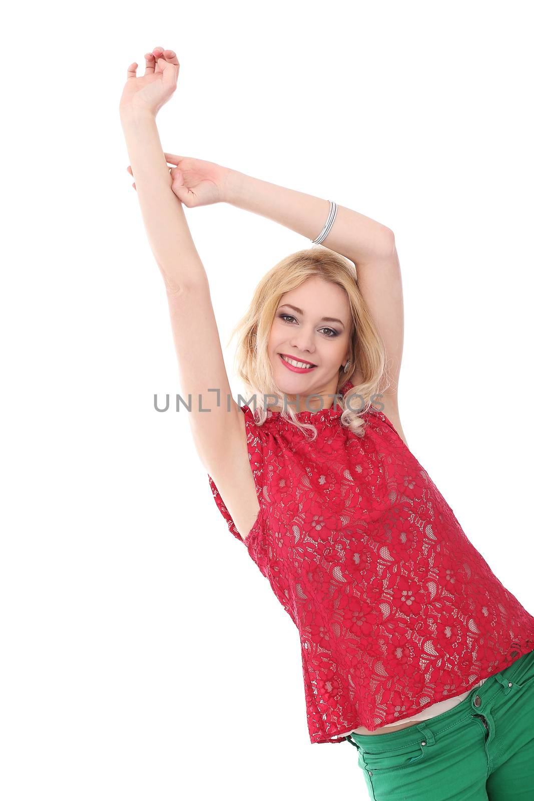 Portrait of a beautiful blonde girl with curly hair who is wearing red blouse and green jeans and posing over a white background