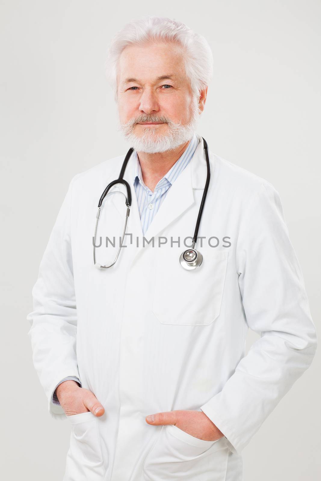 Handsome elderly doctor in uniform isolated over light background