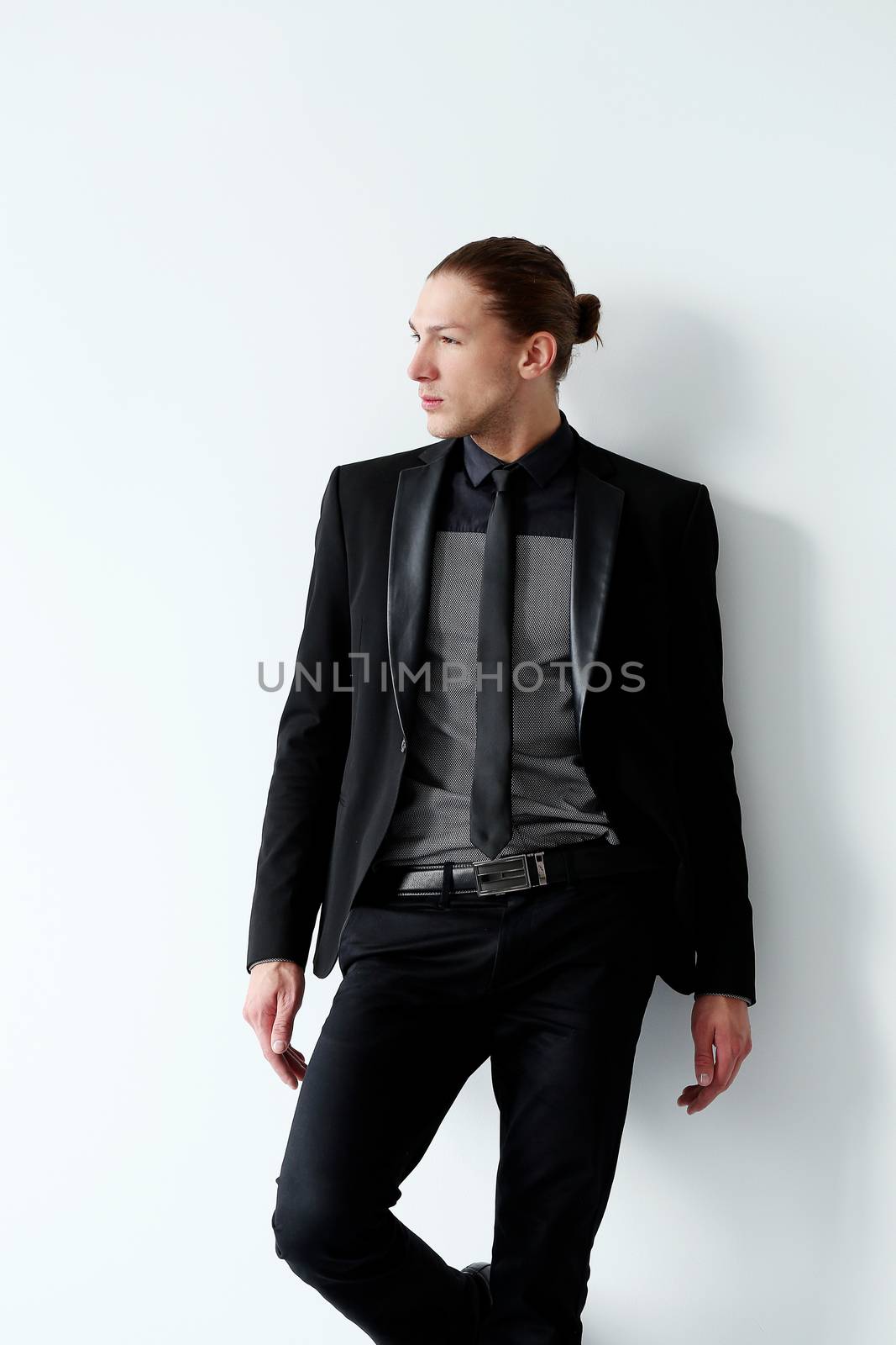 Portrait of a handsome man in a black suit who is posing over a white background