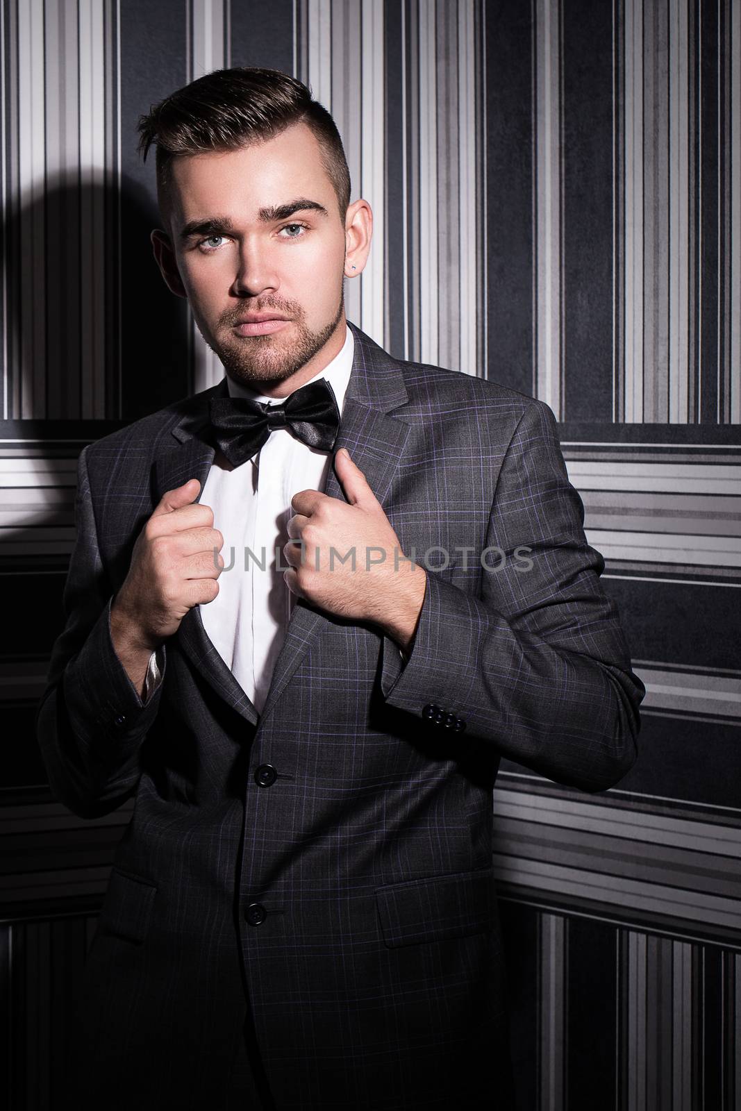 Portrait of a handsome man in a suit and a tie who is posing over a striped background