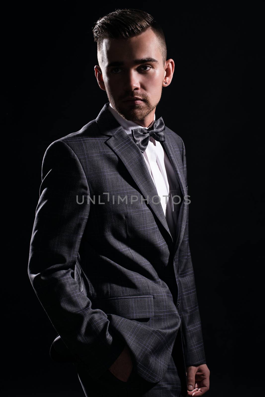 Portrait of a handsome man in a suit who is posing over a black background