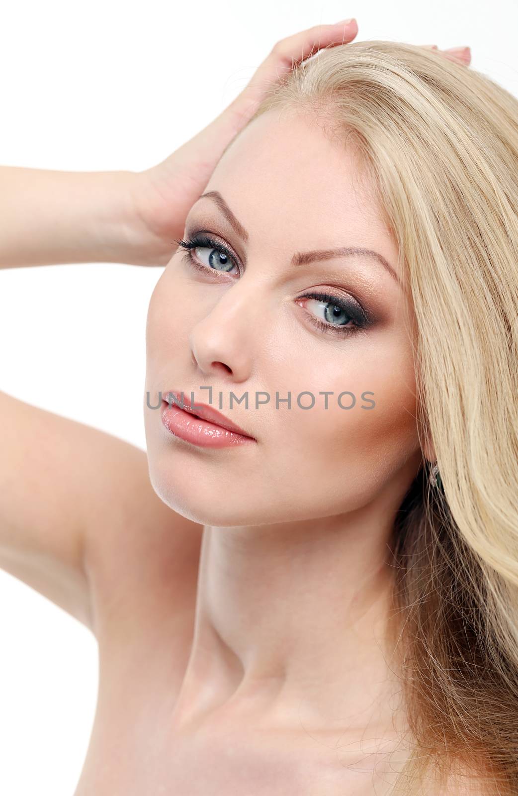 Portrait of a beautiful girl with blonde hair and naked shoulders who is posing over a white background