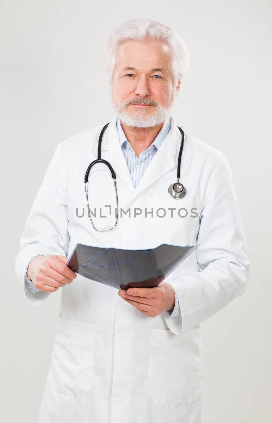 Handsome elderly doctor with radiograph over background