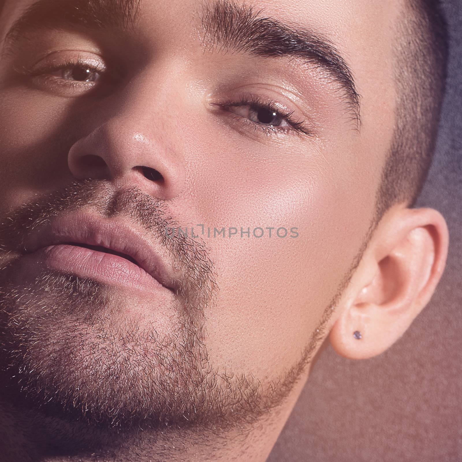 Closeup photo of a handsome man with a beard and an earring
