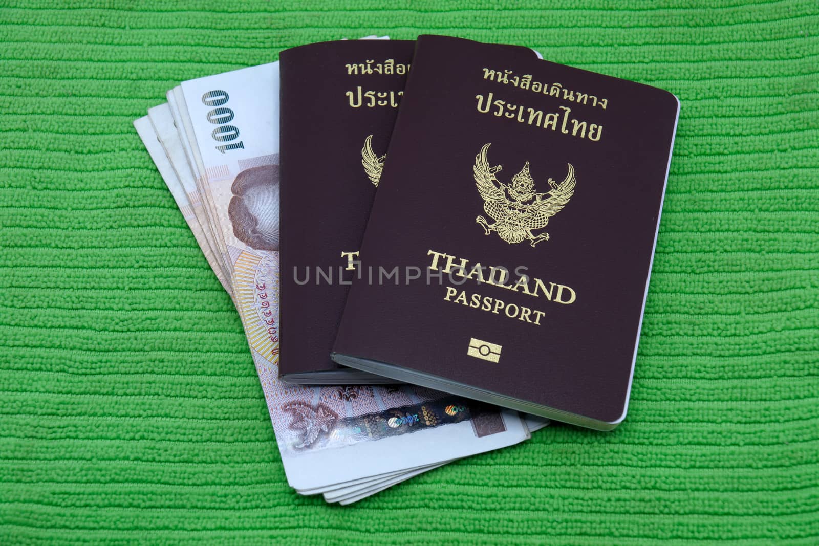 Thailand passport and Thai money isolated on green background