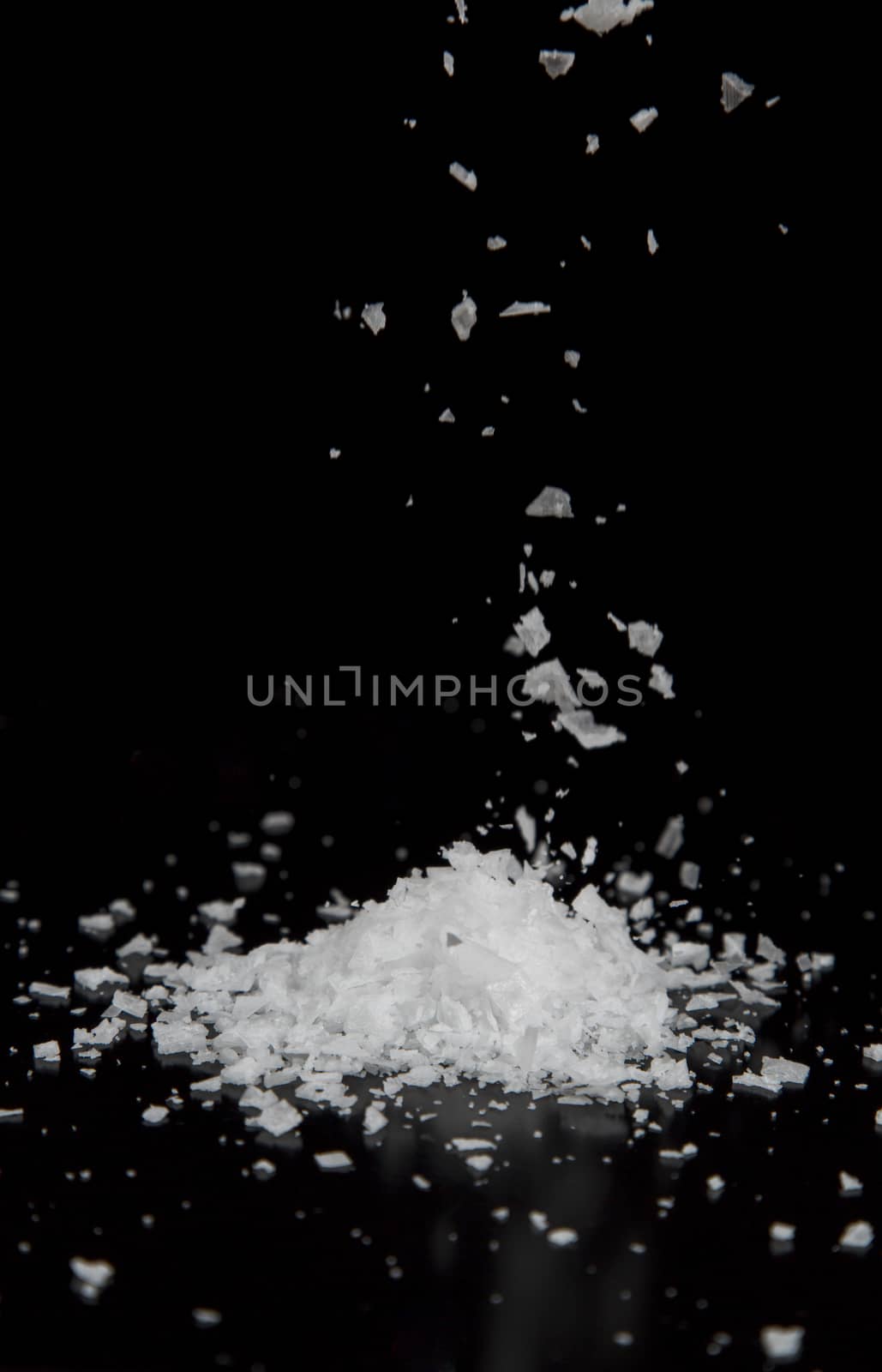 Sea Salt Falling into a Pile with black background.
