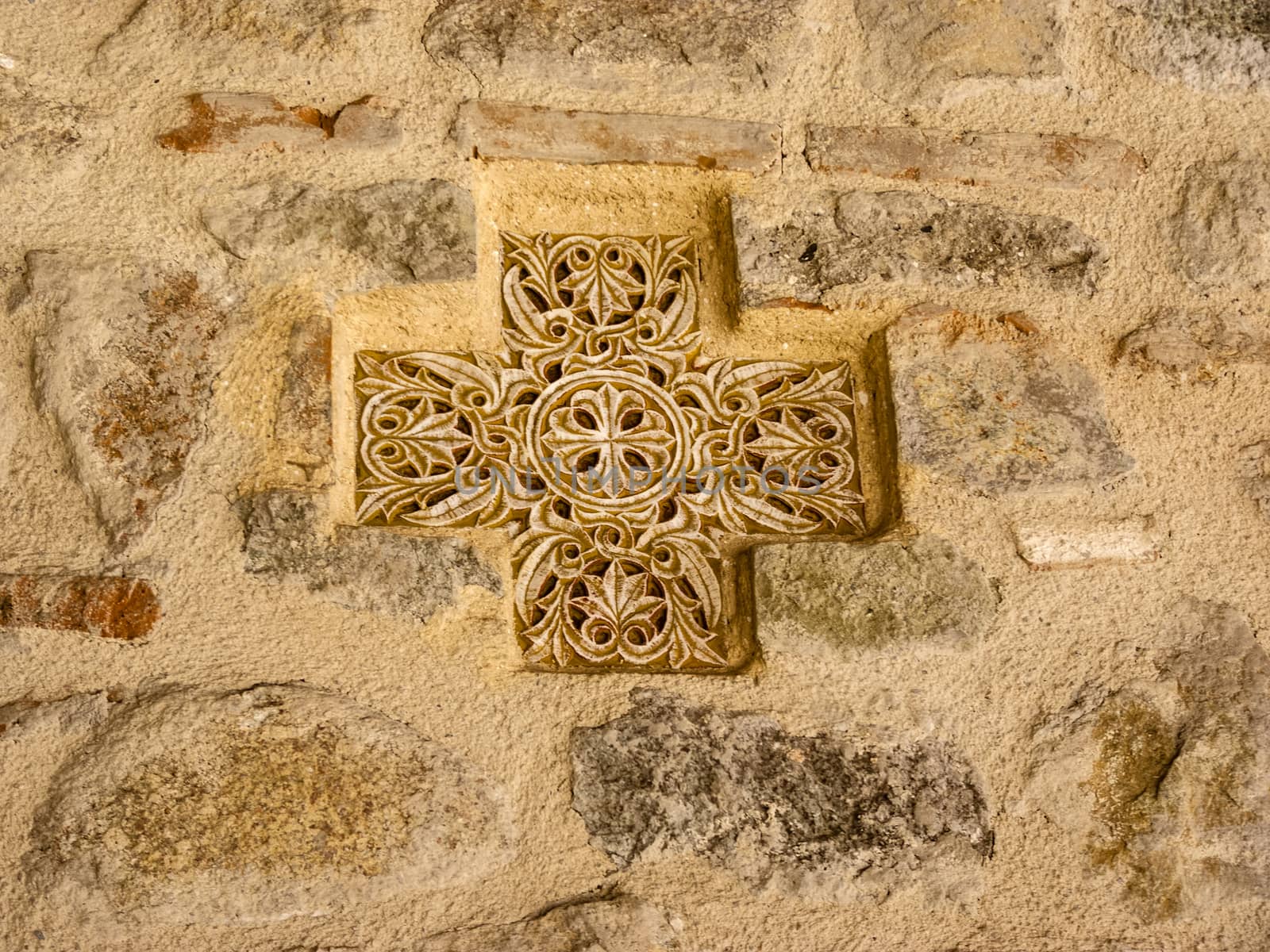 Ancient greek cross on the stone wall. Background