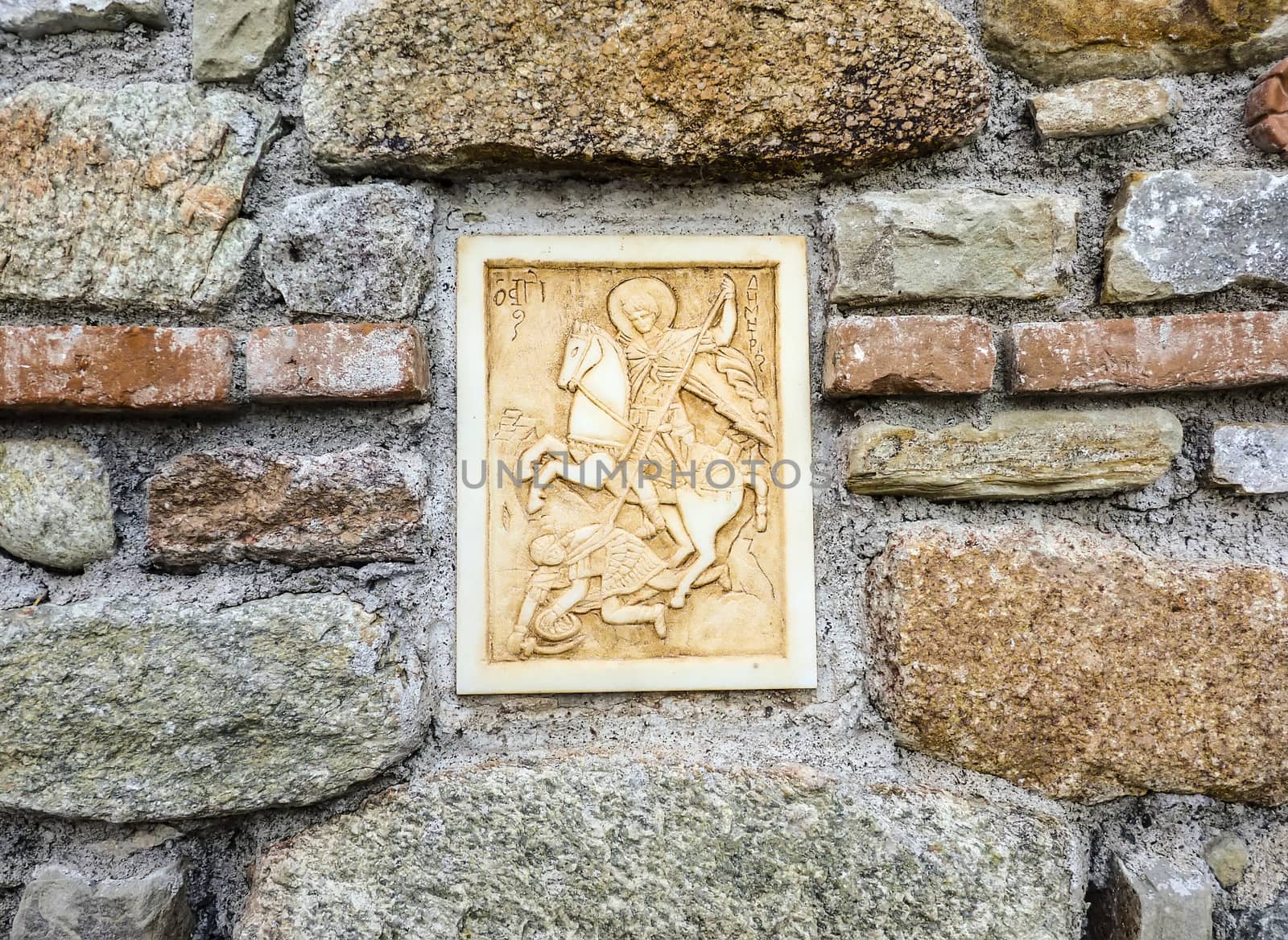 Ancient greek Saint image made of marble on the stone wall. Background