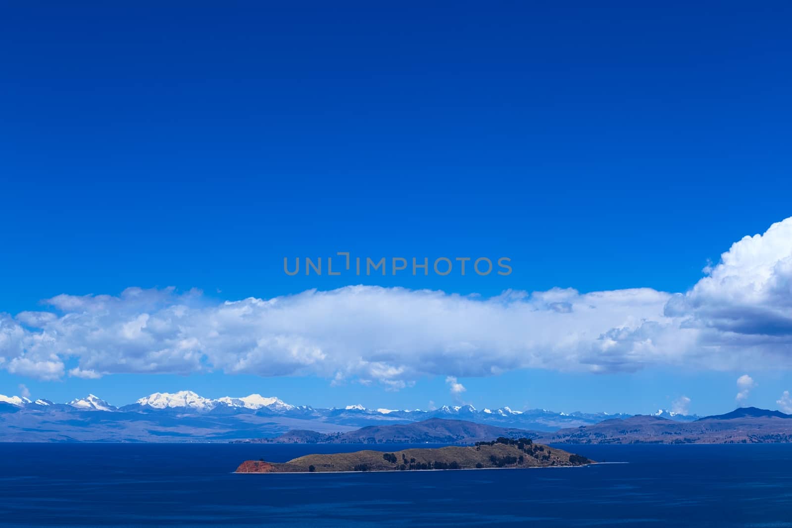The Isla de la Luna (Island of the Moon) with the snow-capped mountains of the Andes in the back photographed from the Isla del Sol (Island of the Sun) in Lake Titicaca, Bolivia. The islands are a popular travel destination.  