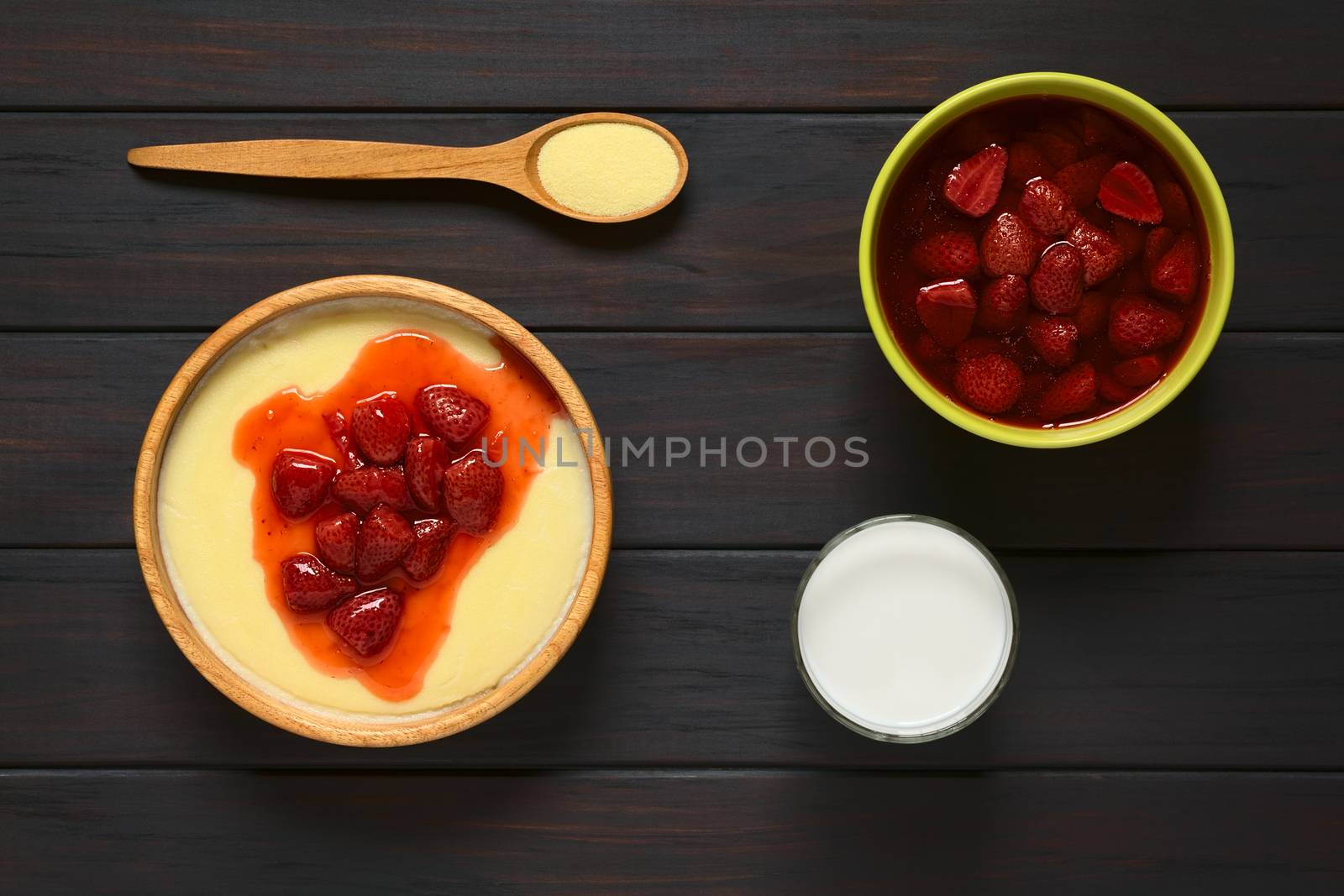 Overhead shot of semolina pudding with strawberry compote served in wooden bowl, photographed on dark wood with natural light  