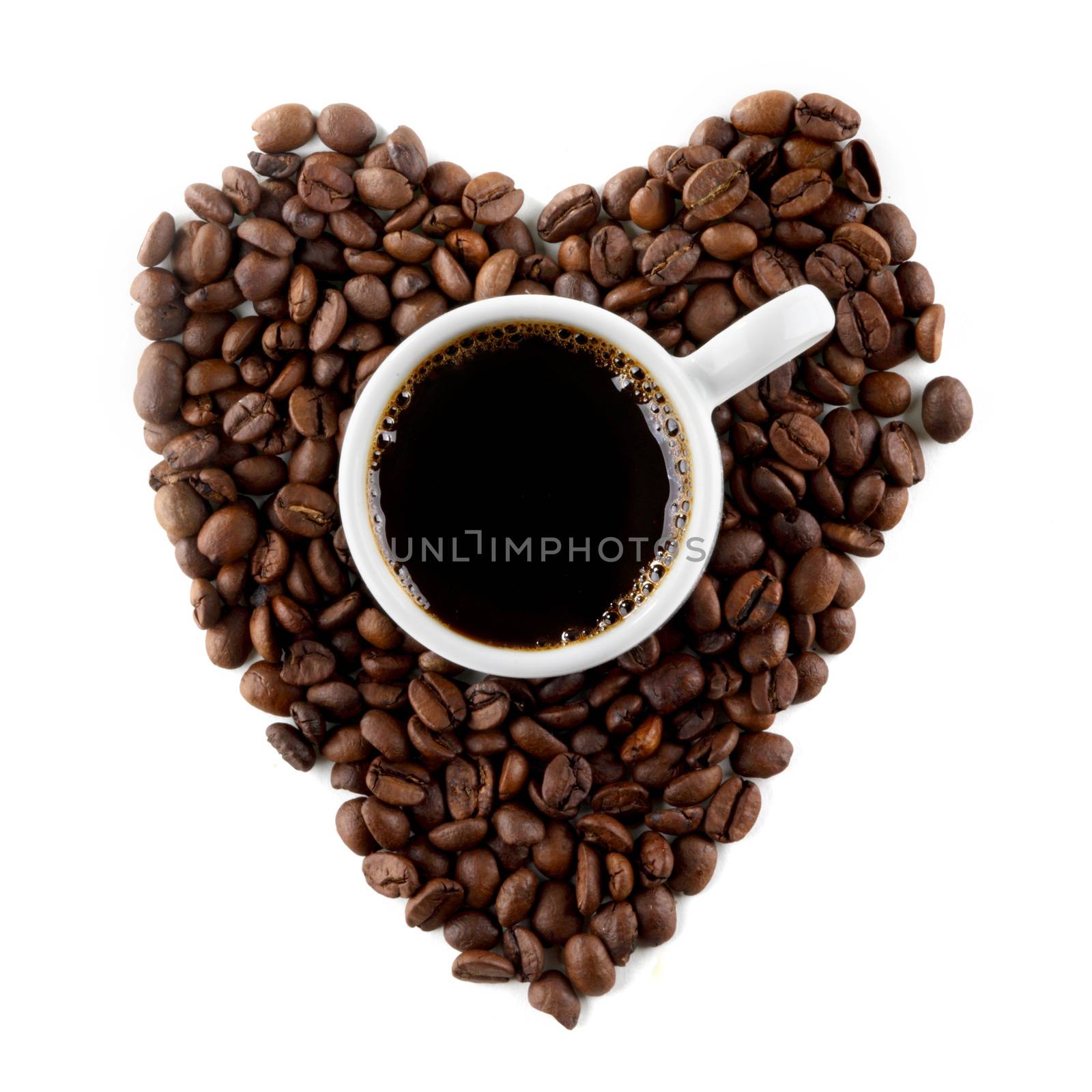 Cup of coffee on coffee beans shaped as a heart isolated on white background