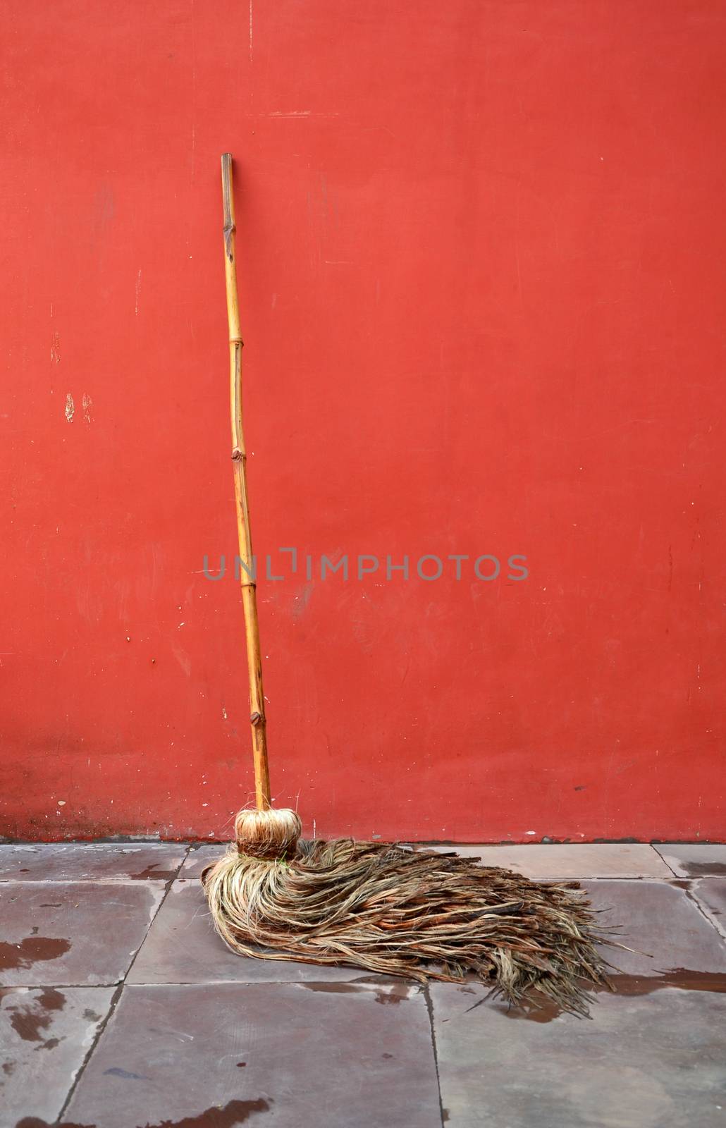 Mop lean against red wall by siraanamwong