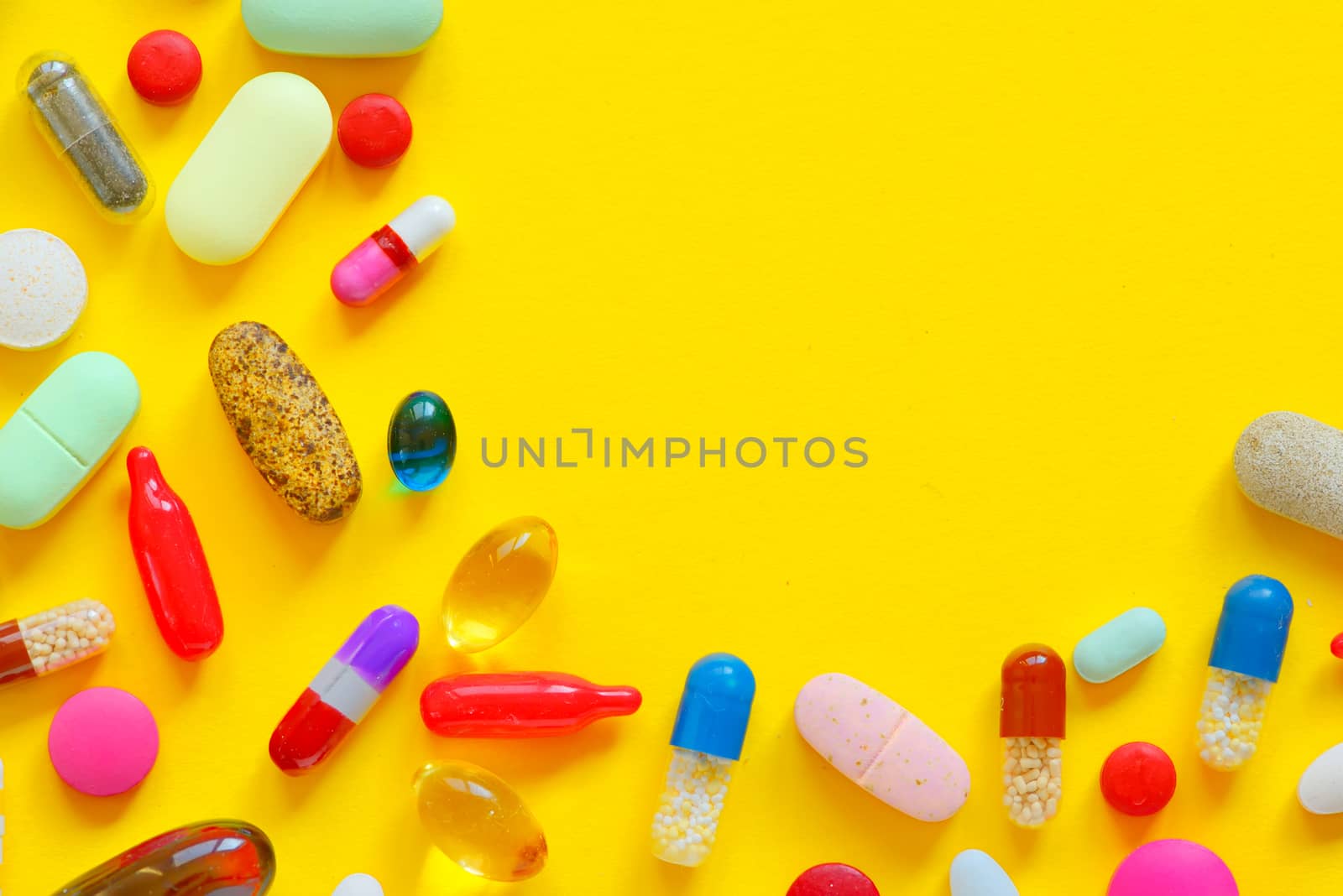 Many colorful pills isolated on yellow background