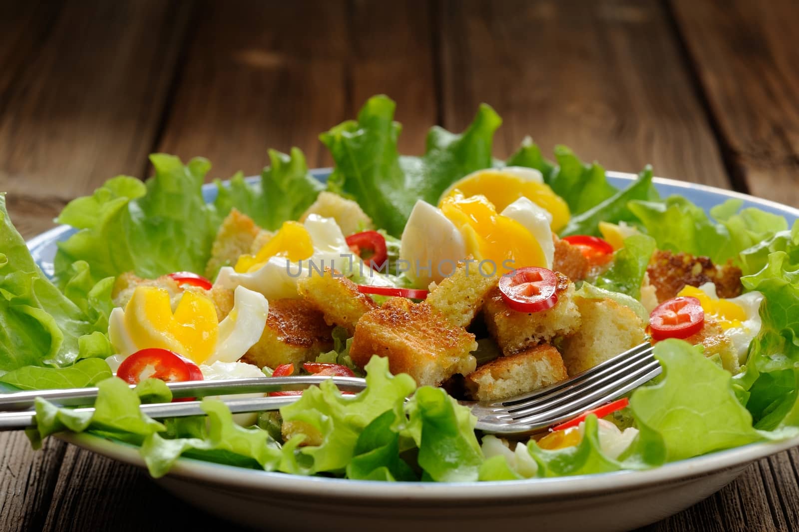 Salad Caesar with eggs, chili pepper and two forks closeup by Borodin