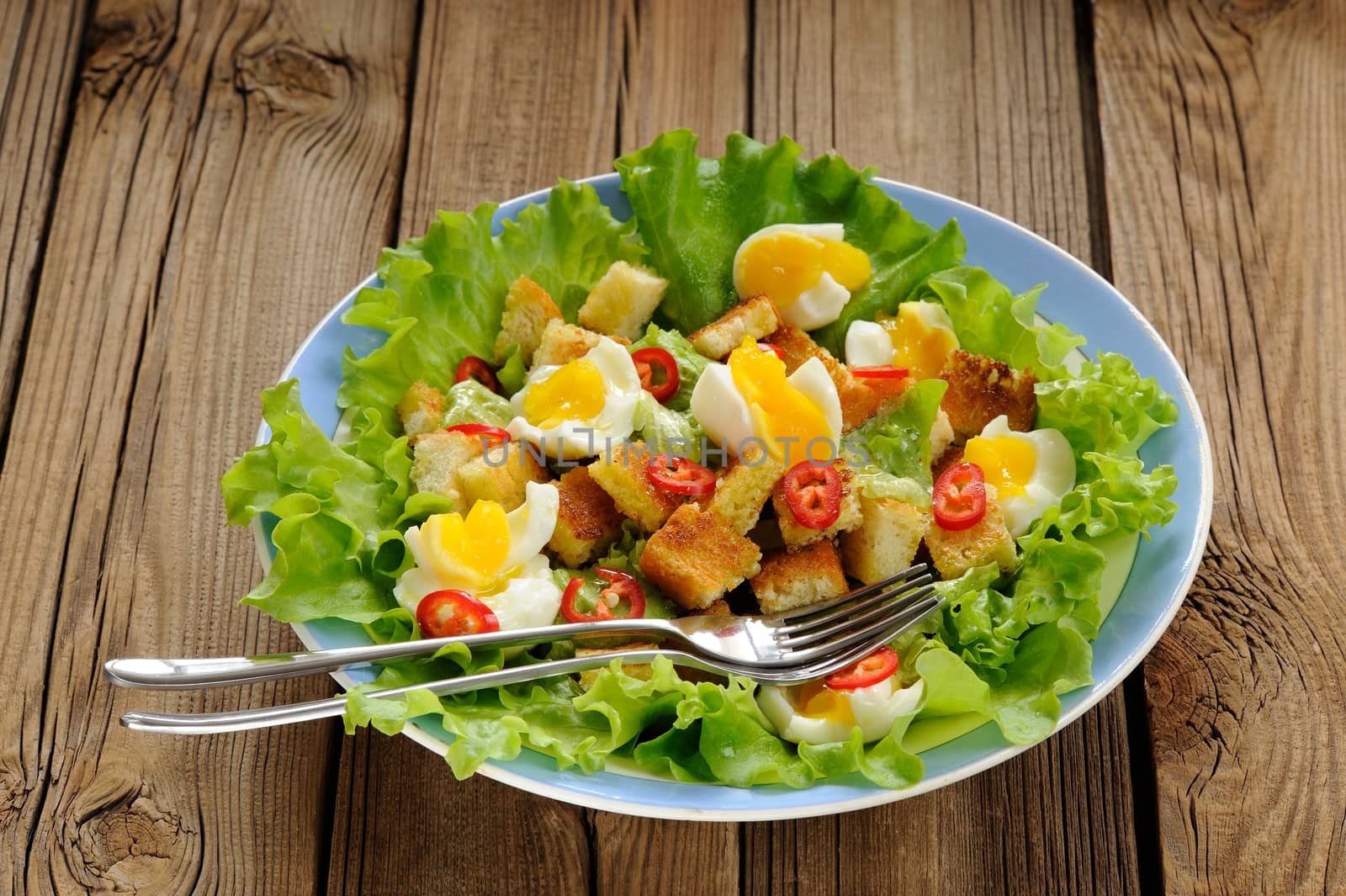 Salad Caesar with eggs, chili pepper and two forks