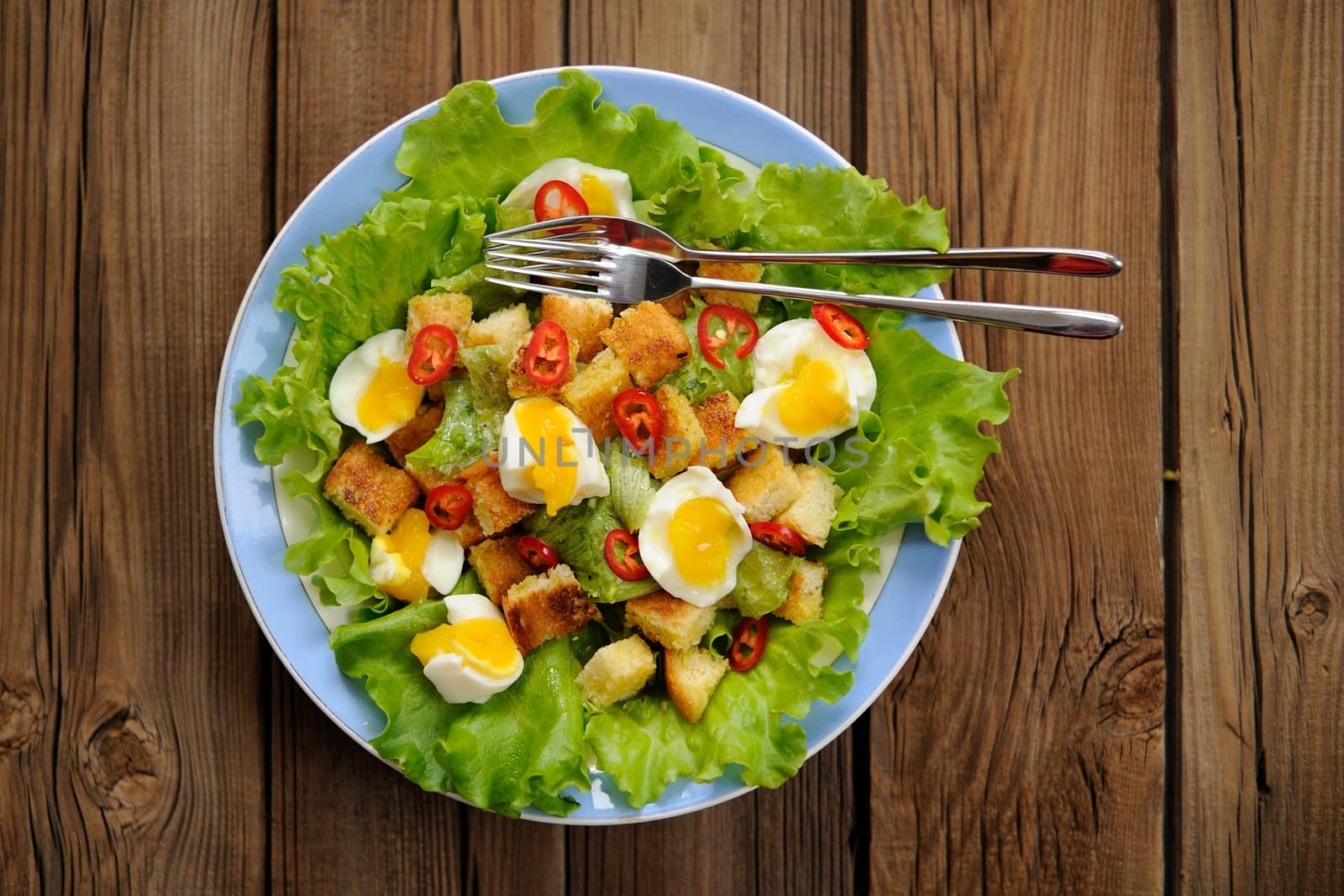 Salad Caesar with eggs, chili pepper and two forks top view by Borodin