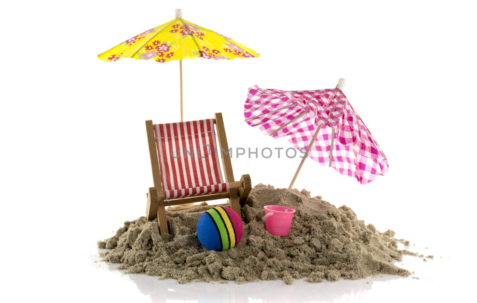 yellow and pink parasol in the sand with ball and bucket on the beach