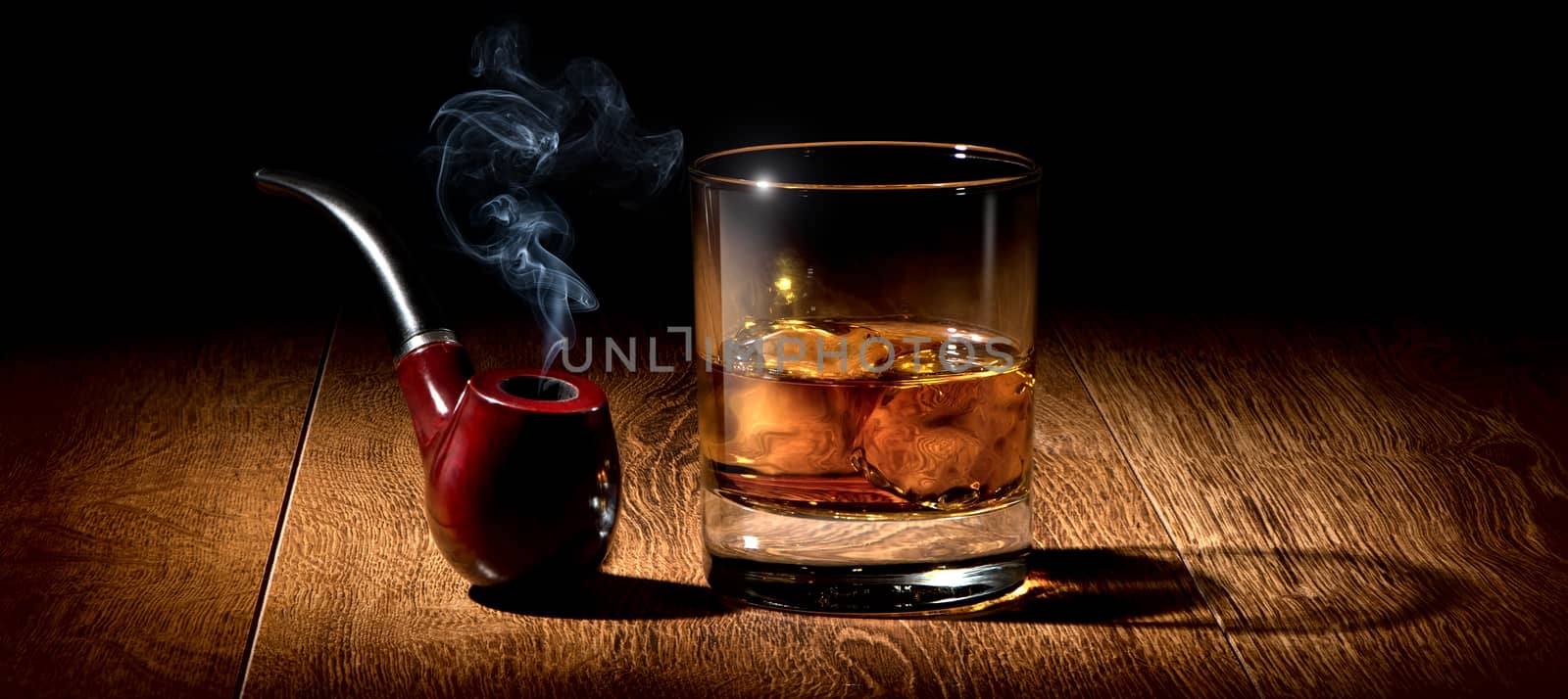 Tobacco pipe and glass of scotch on wooden table