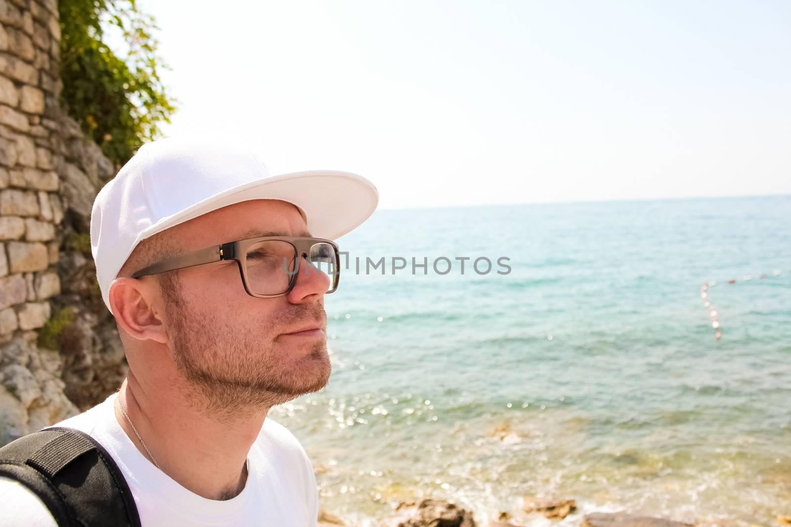 Handsome young man against bright beach background