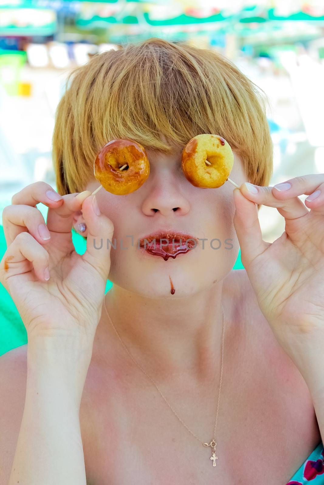 Playful girl holding donuts on her eyes. Woman showing own. 