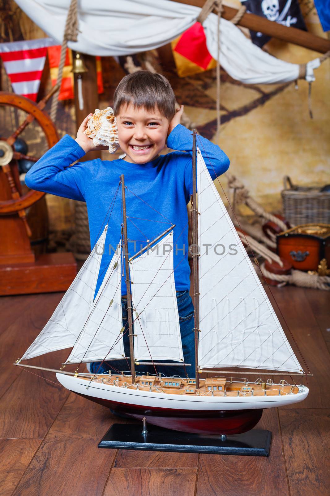 Cute little boy with ship toy on the deck of a ship