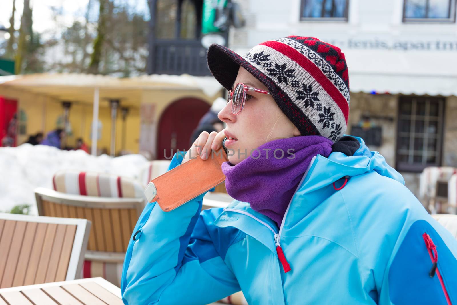 Woman on winter vacations in ski resort using smartphone.