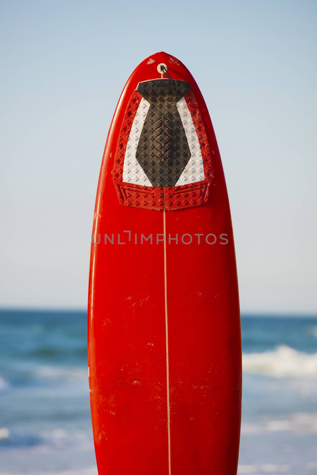 Red surfboard on the sand on a very beautiful sunny day