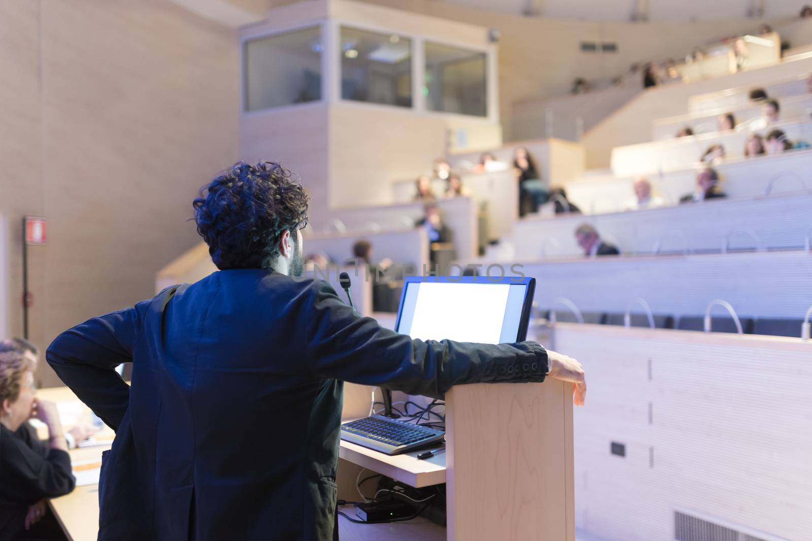 Speaker giving talk on podium at Business Conference. Business and Entrepreneurship. Expert presenting his work in lectures hall.