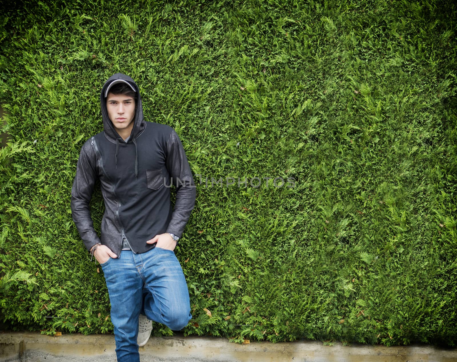 Handsome young man in black hoodie sweater standing outdoor by artofphoto