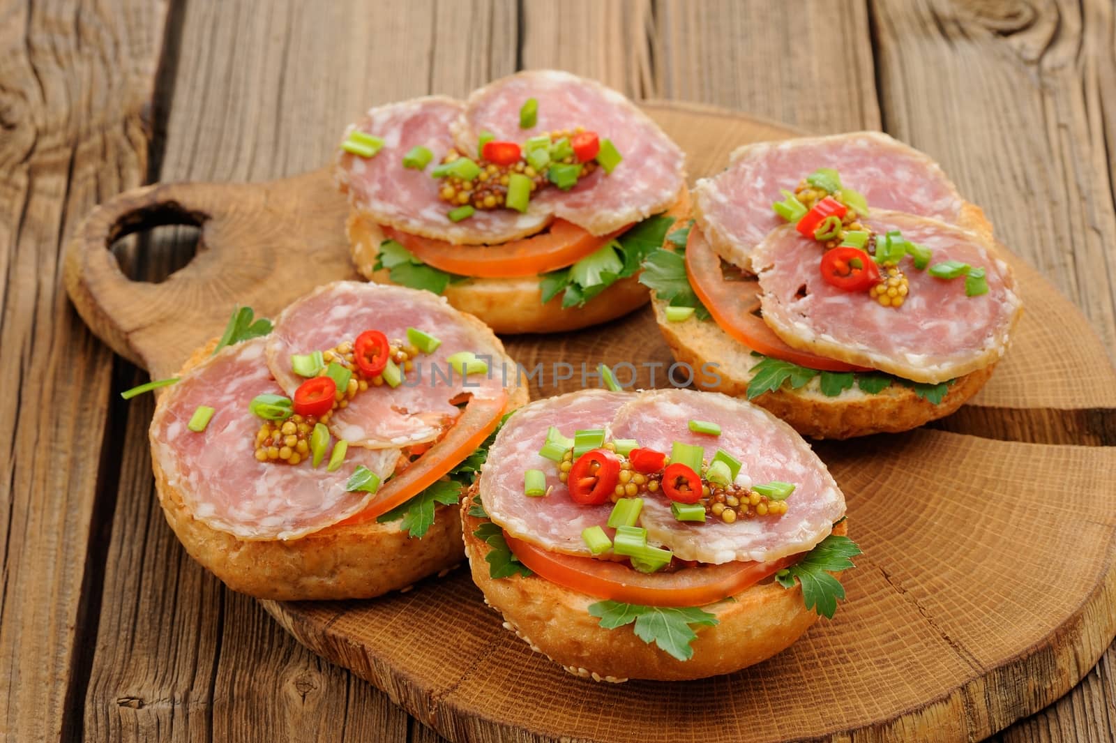 Ham sandwiches with chili, parsley and scallion on wooden board by Borodin
