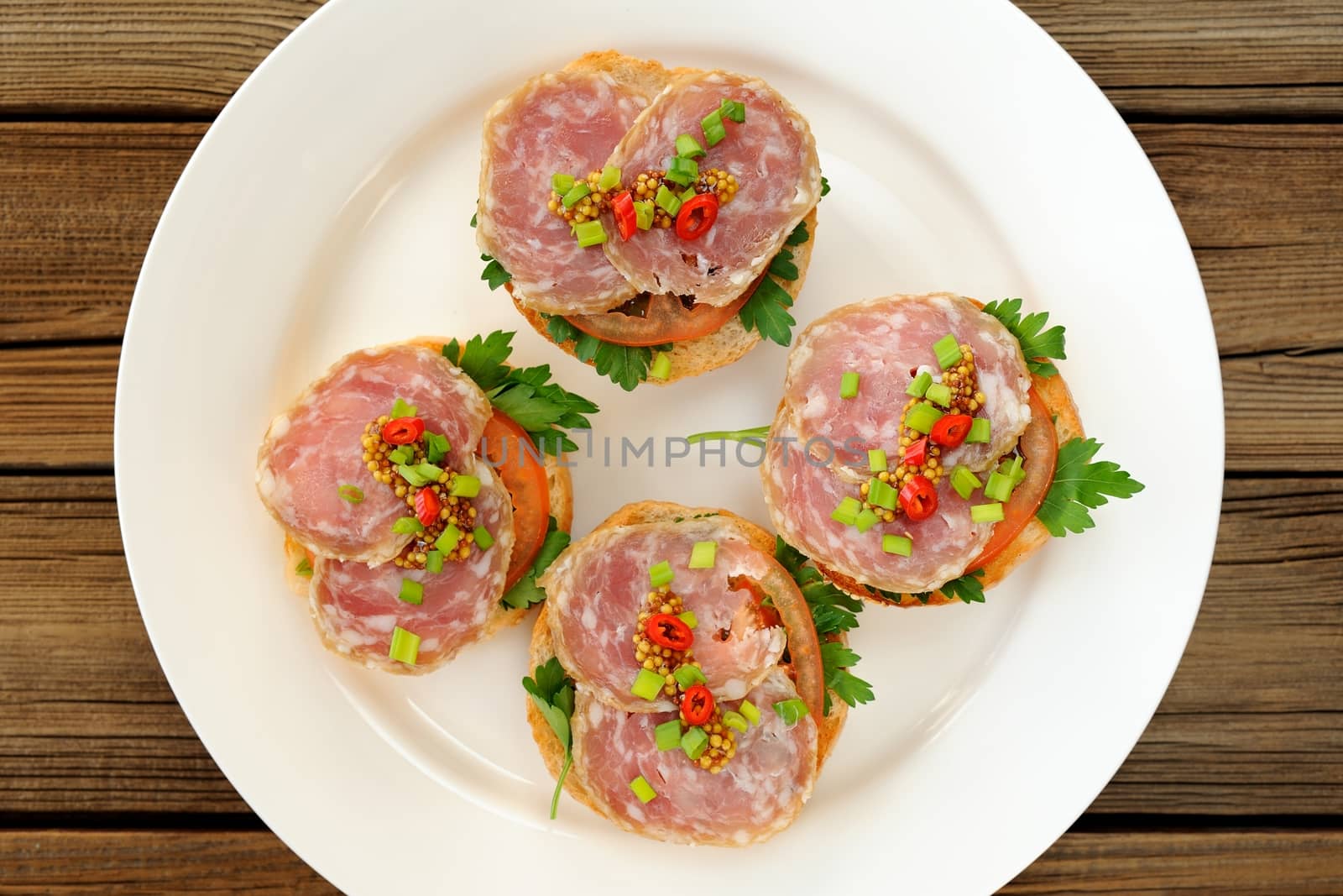 Ham sandwiches with chili, parsley and scallion on white plate top view horizontal