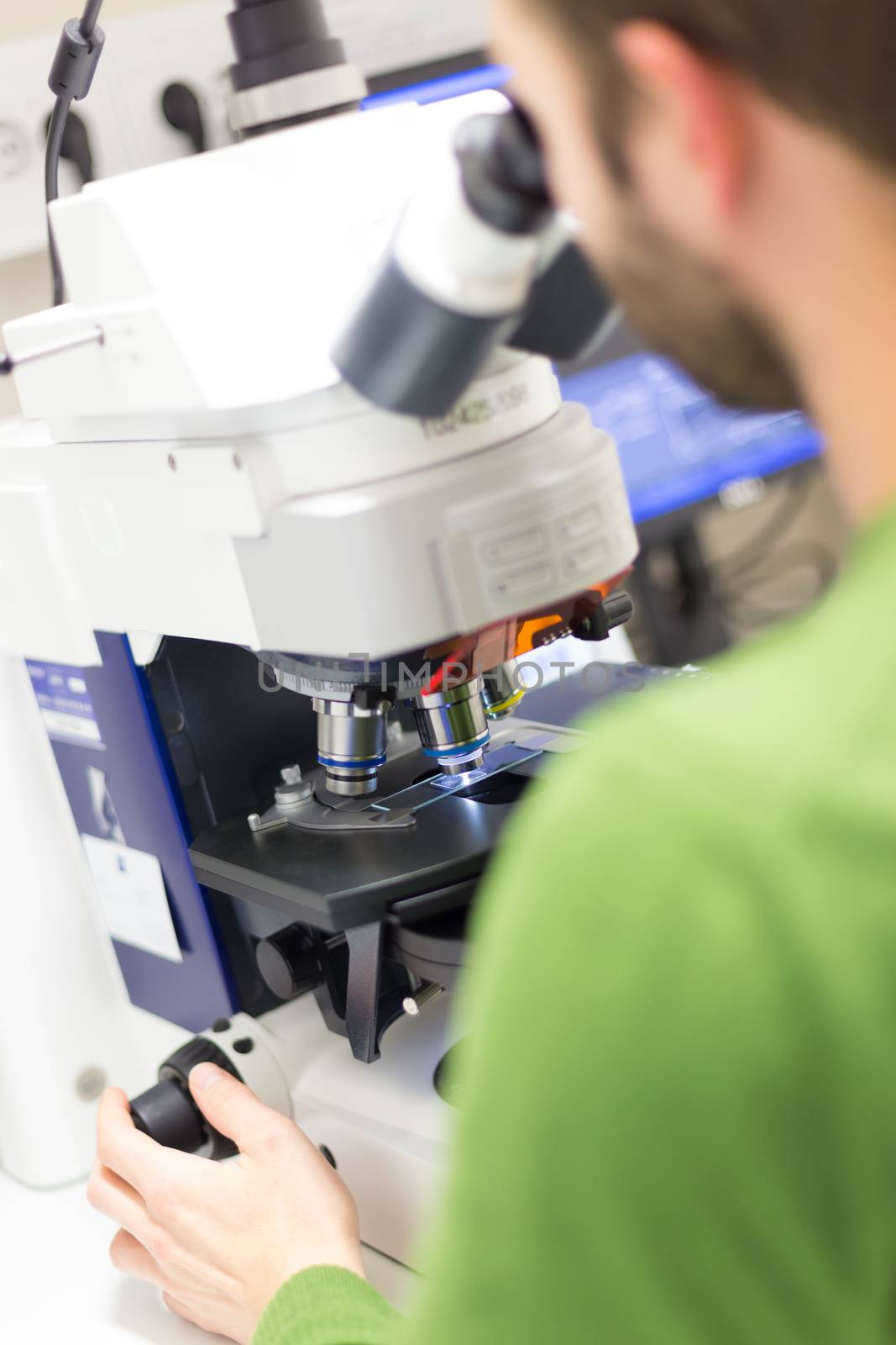 Scientist microscoping on fluorescent microscope.  by kasto