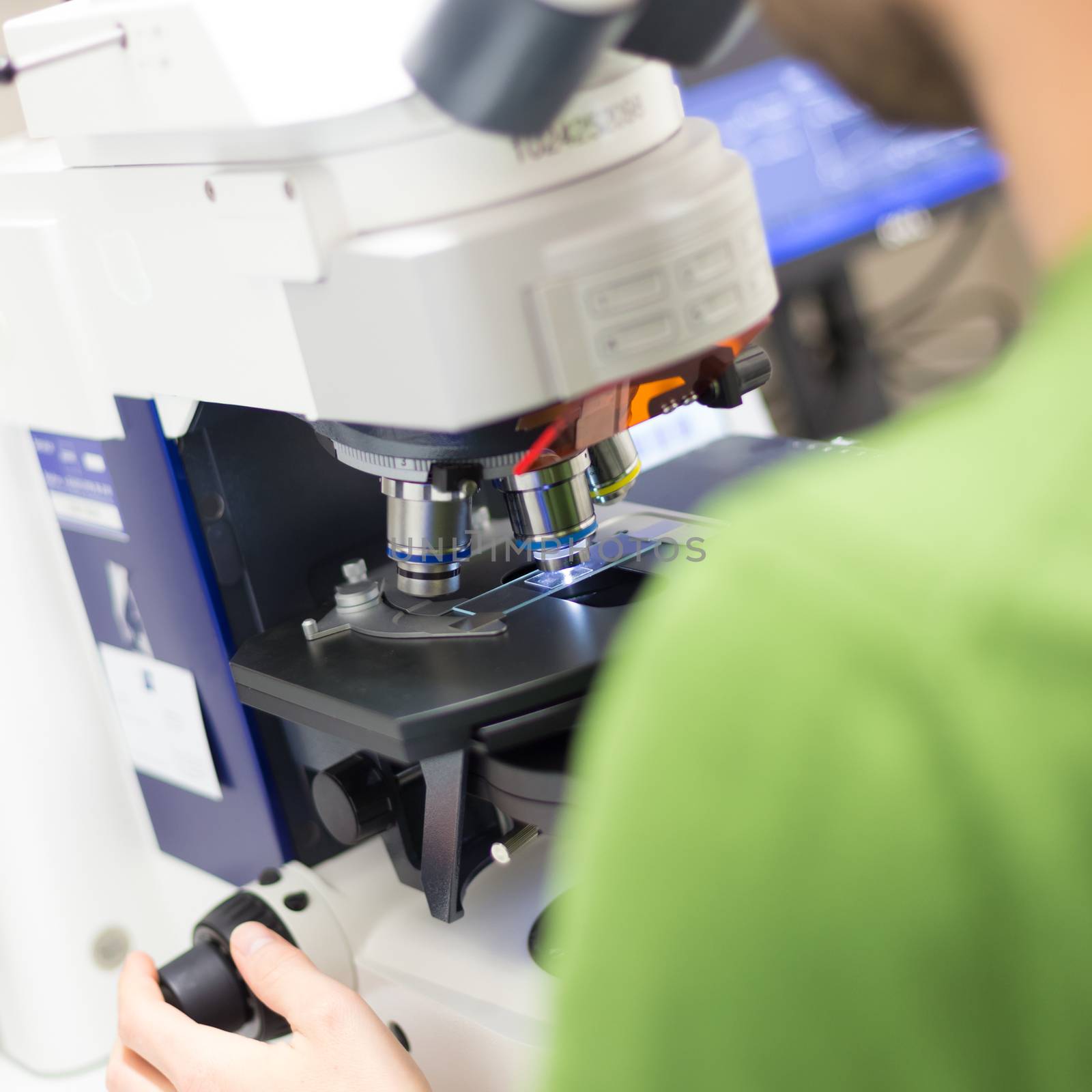 Male scientist microscoping on hi-tec fluorescent microscope. 