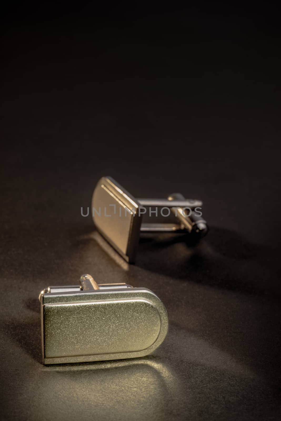 A pair of cufflinks on a dark counter top.