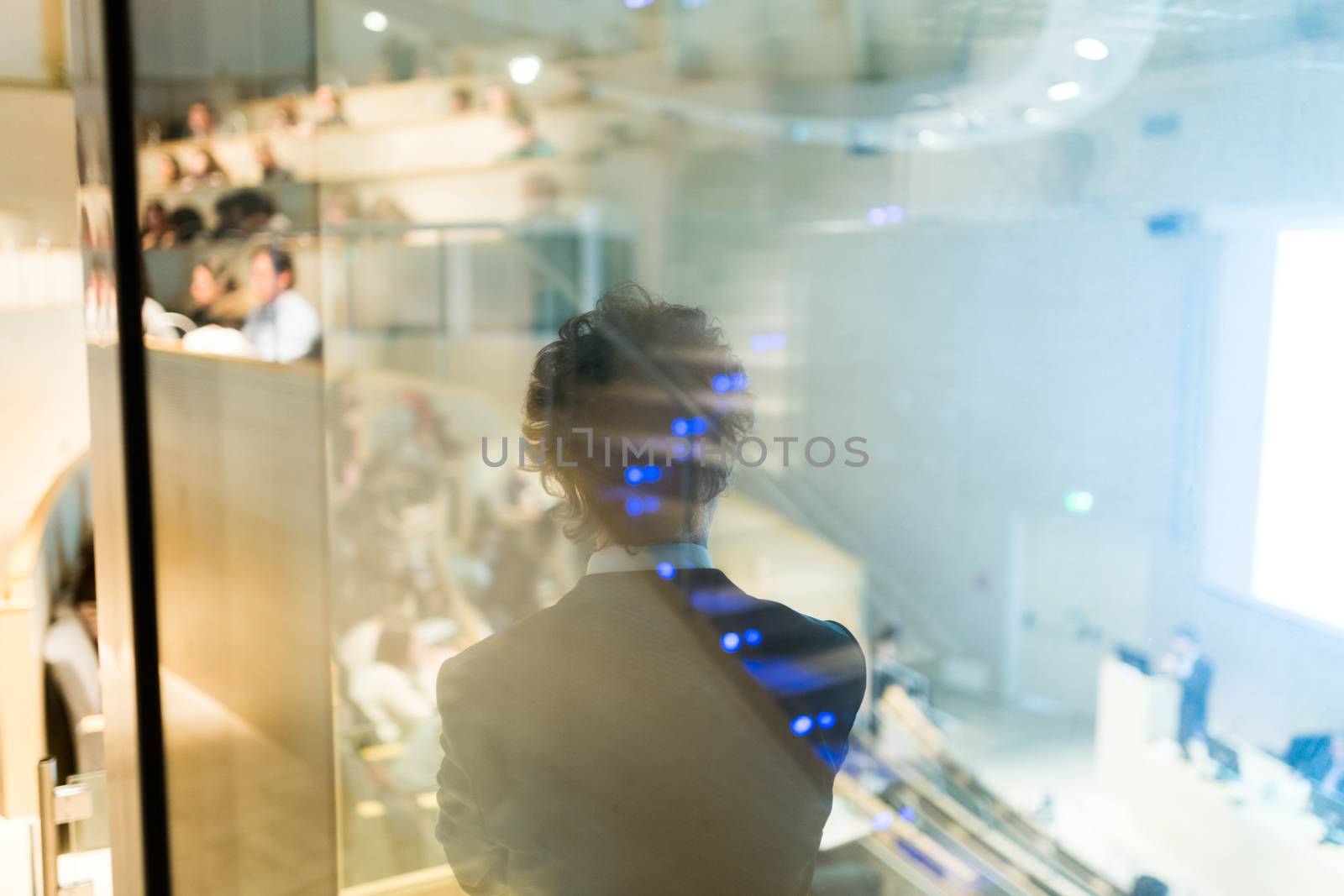 Rear, through the window, view of businessman at Business Conference. Abstract reflection of participants in the glass. Audience at the conference hall. Business and Entrepreneurship.