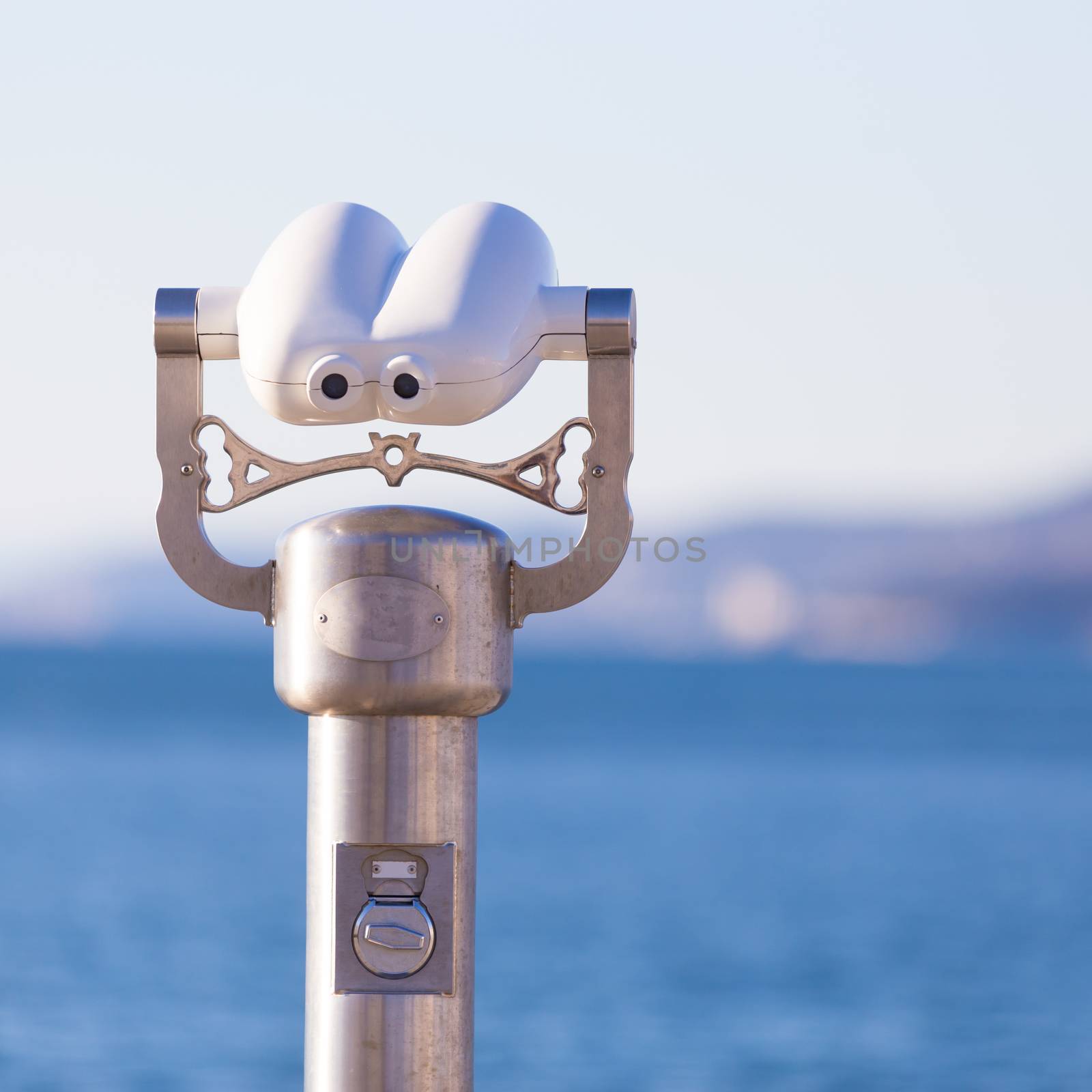 Telescope on a beach pointed at blue sea.