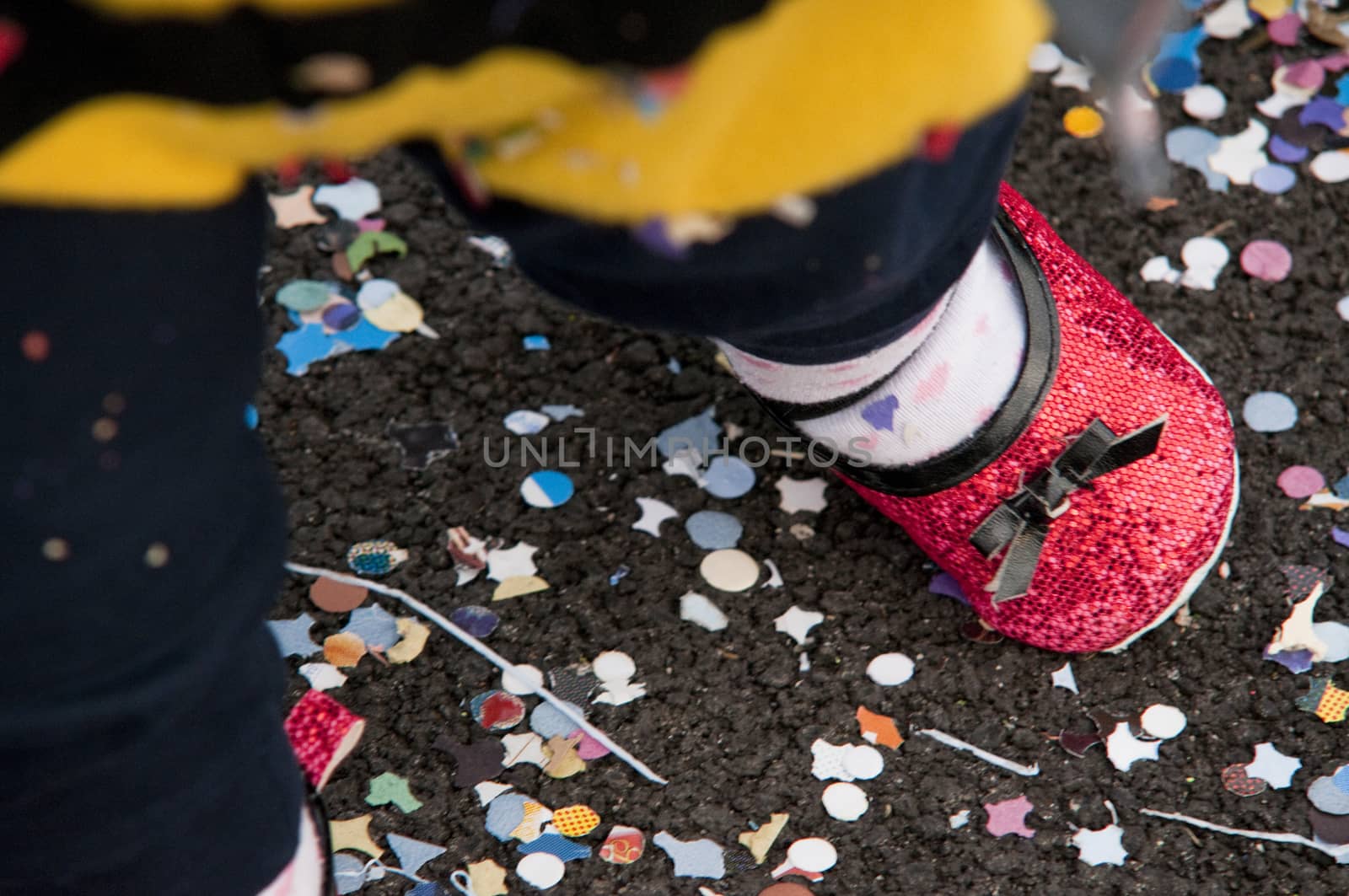 leg of a child with her shoe during the carnival with many confetti